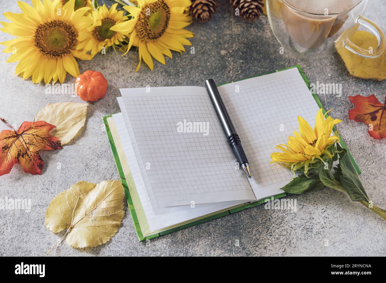 Guten Morgen. To-do-Listenkonzept. Ein Strauß großer Sonnenblumen, Kaffeetasse und leeres Notizbuch auf einem Steintisch. Stockfoto