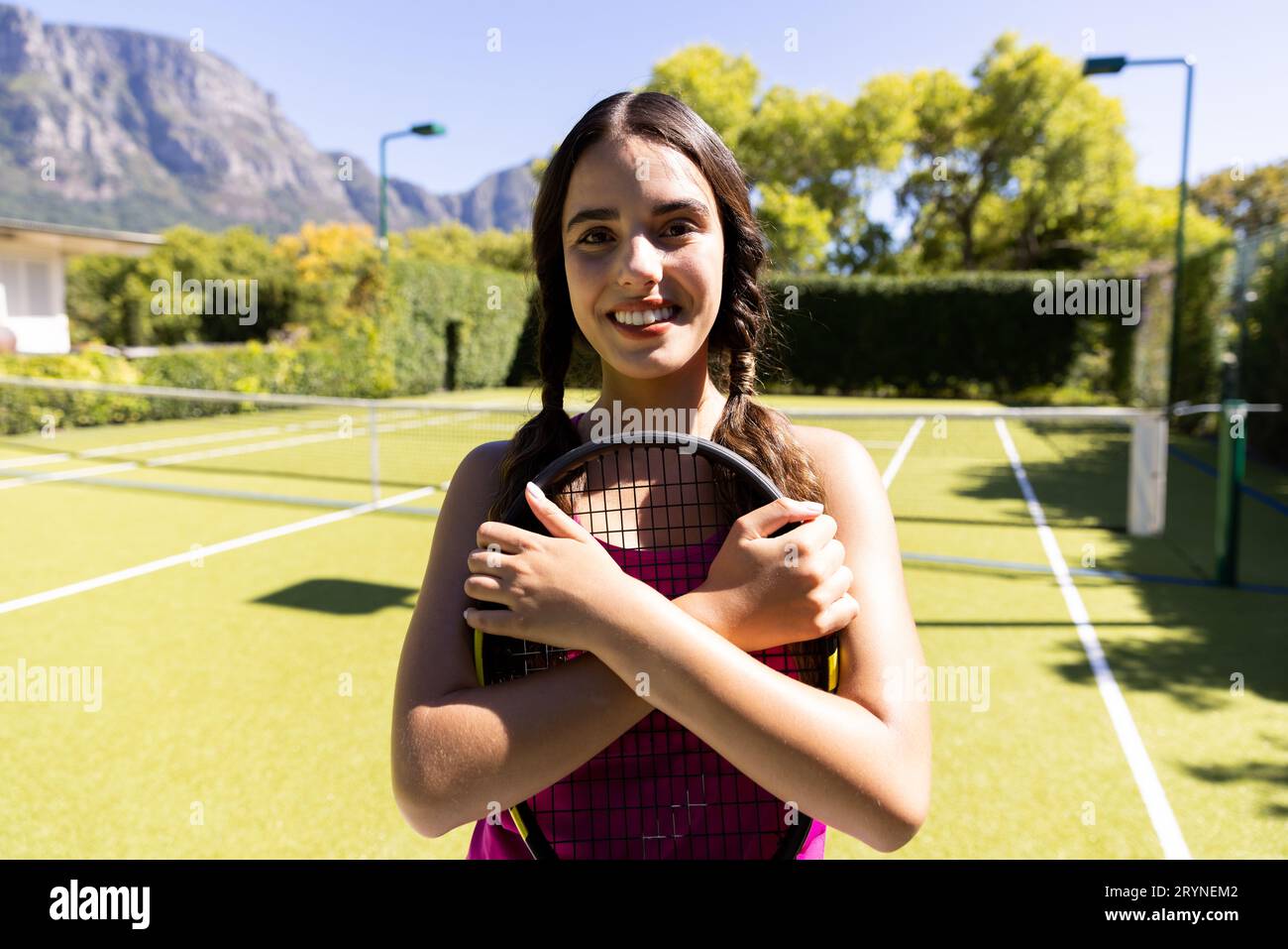 Porträt einer birassischen jungen Frau, die auf dem Tennisplatz einen lächelnden Tennisschläger hält Stockfoto