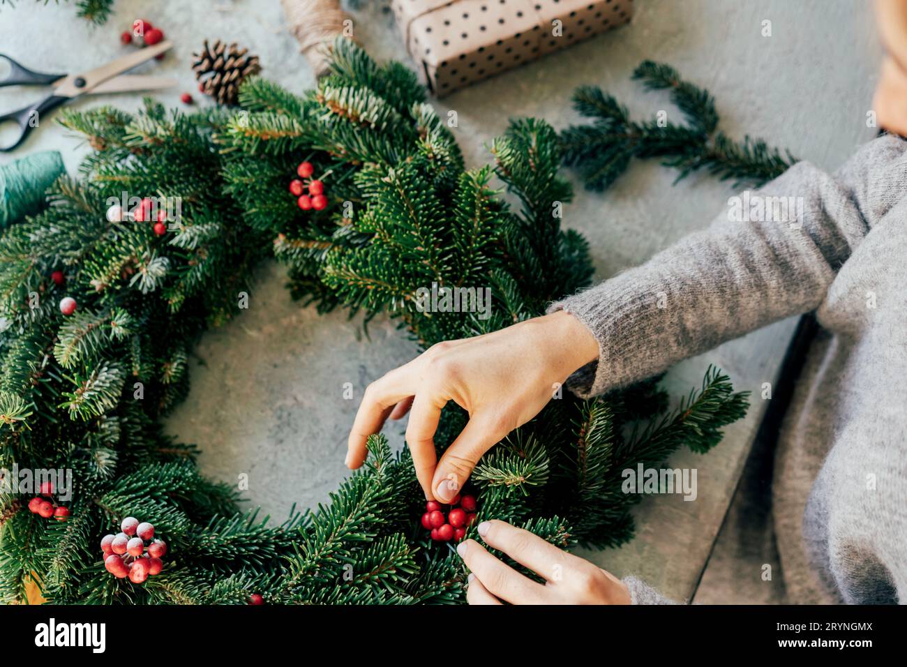 Eine Frau bastelt zu Weihnachten einen Kranz. Natürliche Dekoration Stockfoto