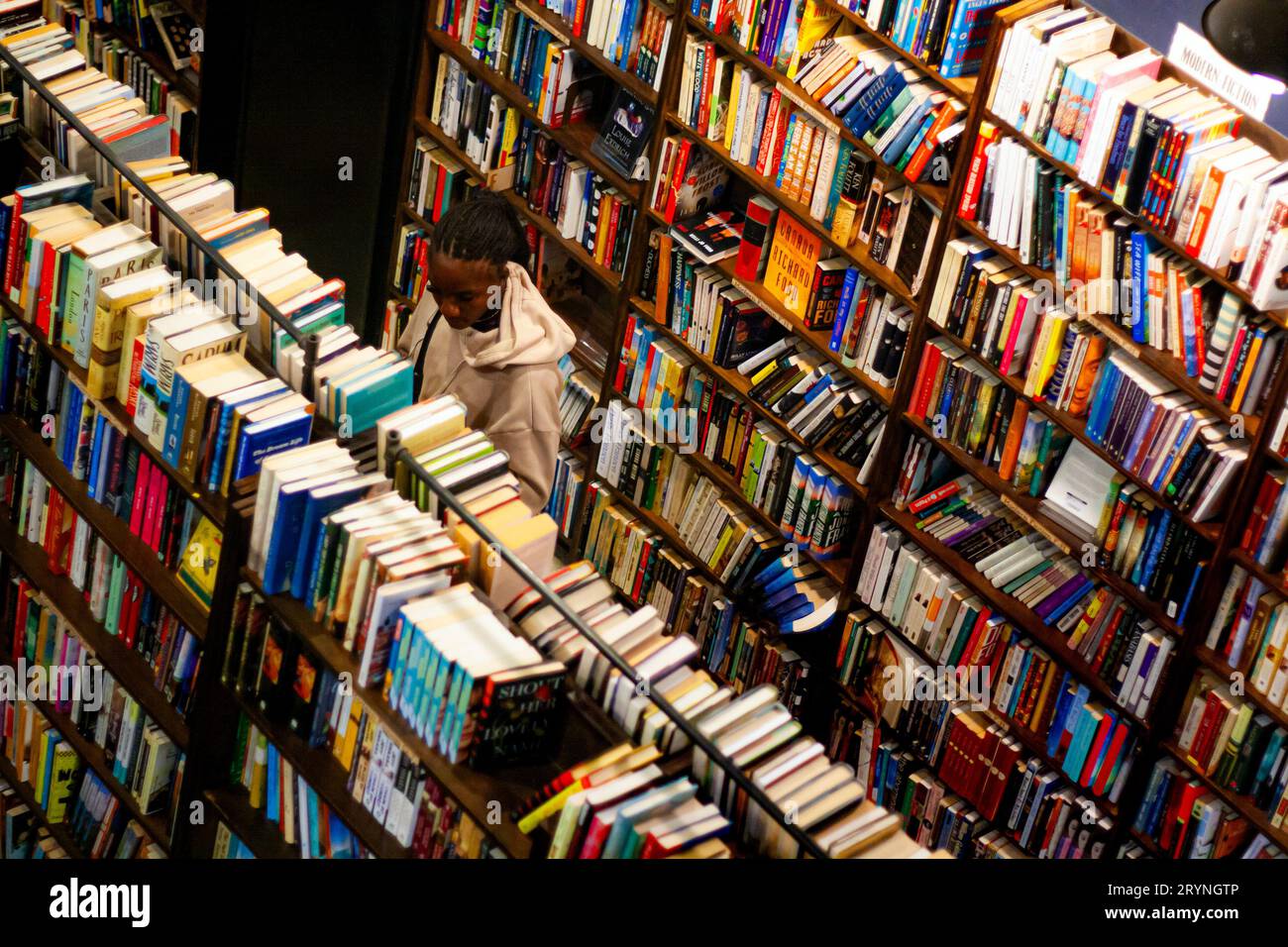 Eine junge Frau, die in einem Buchladen Bücher durchsucht Stockfoto