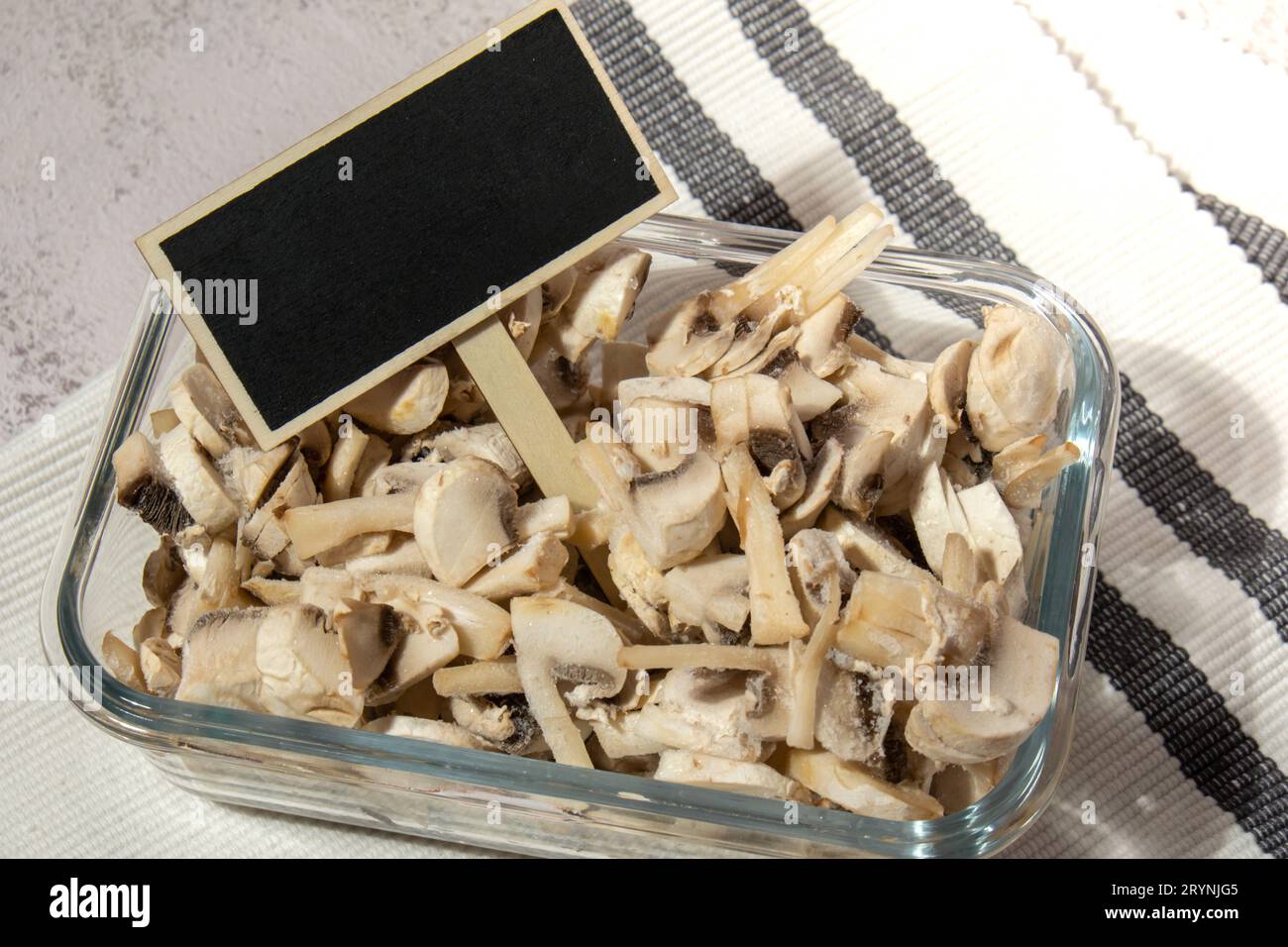 Tiefkühlkost in Scheiben geschnittene Pilze Champignon mit Tafel Holzetikett Kopierraum für Text hausgemacht. Erntekonzept. Strumpf Stockfoto