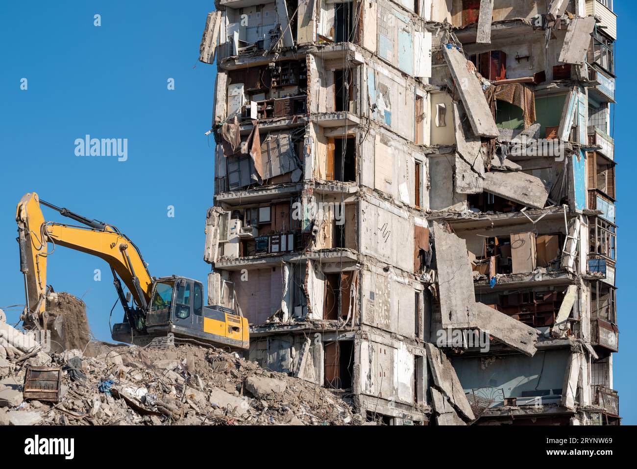 Baumaschinen zerstören Häuser, die während des Krieges in der Ukraine beschädigt wurden Stockfoto