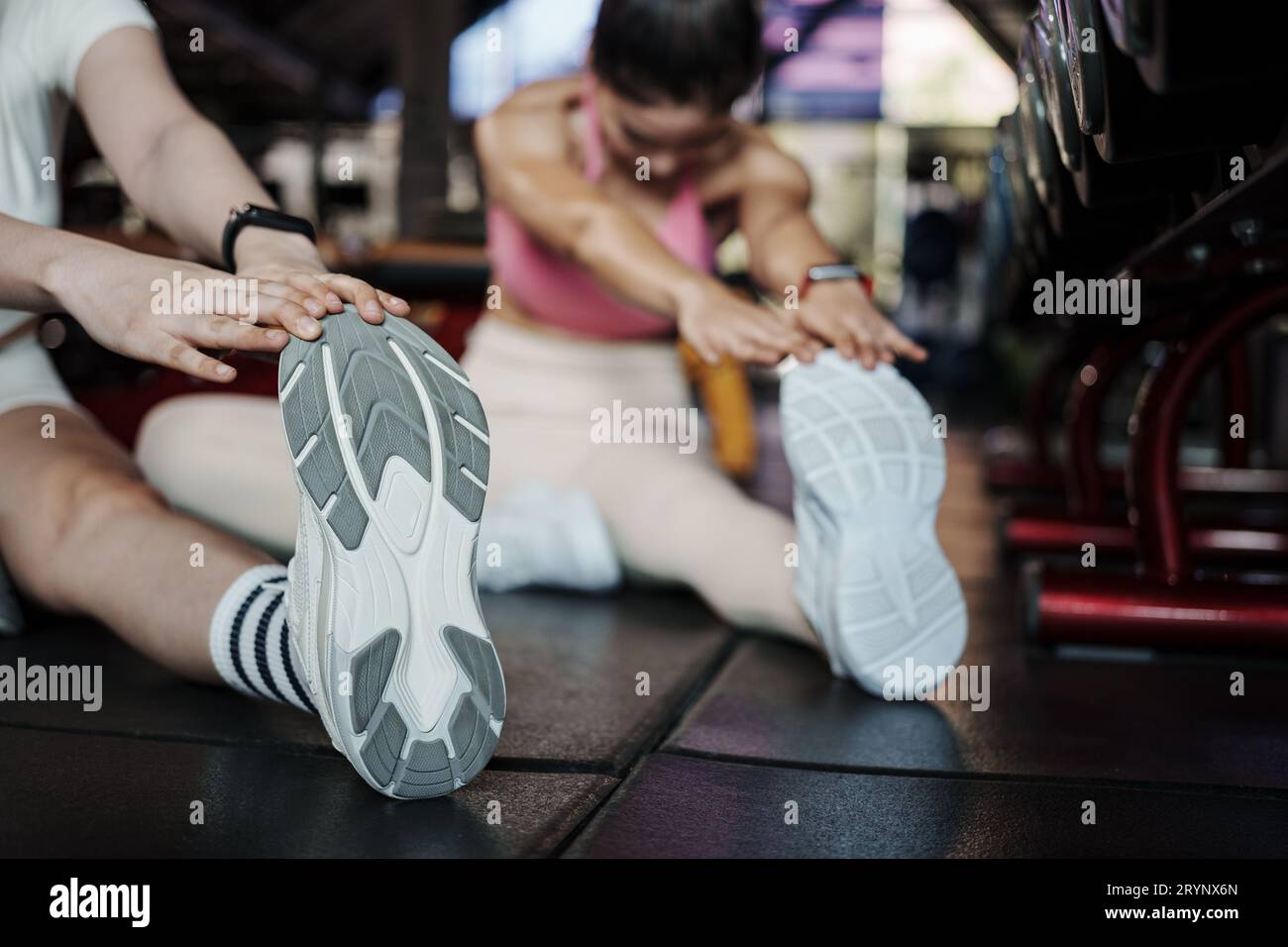 Fitness, Stretching und zwei Frauen im Fitnessstudio für ein warm-up-Workout, Training und Body Wellness mit Übung. Junge Sportlerin oder Athletin auf dem Boden bis s Stockfoto