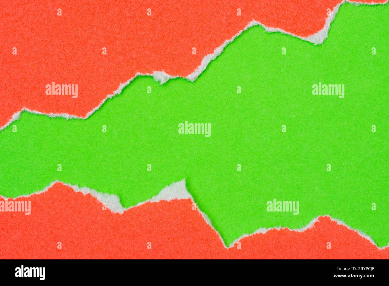 Loch in rotem Papier auf grünem Hintergrund gerissen Stockfoto