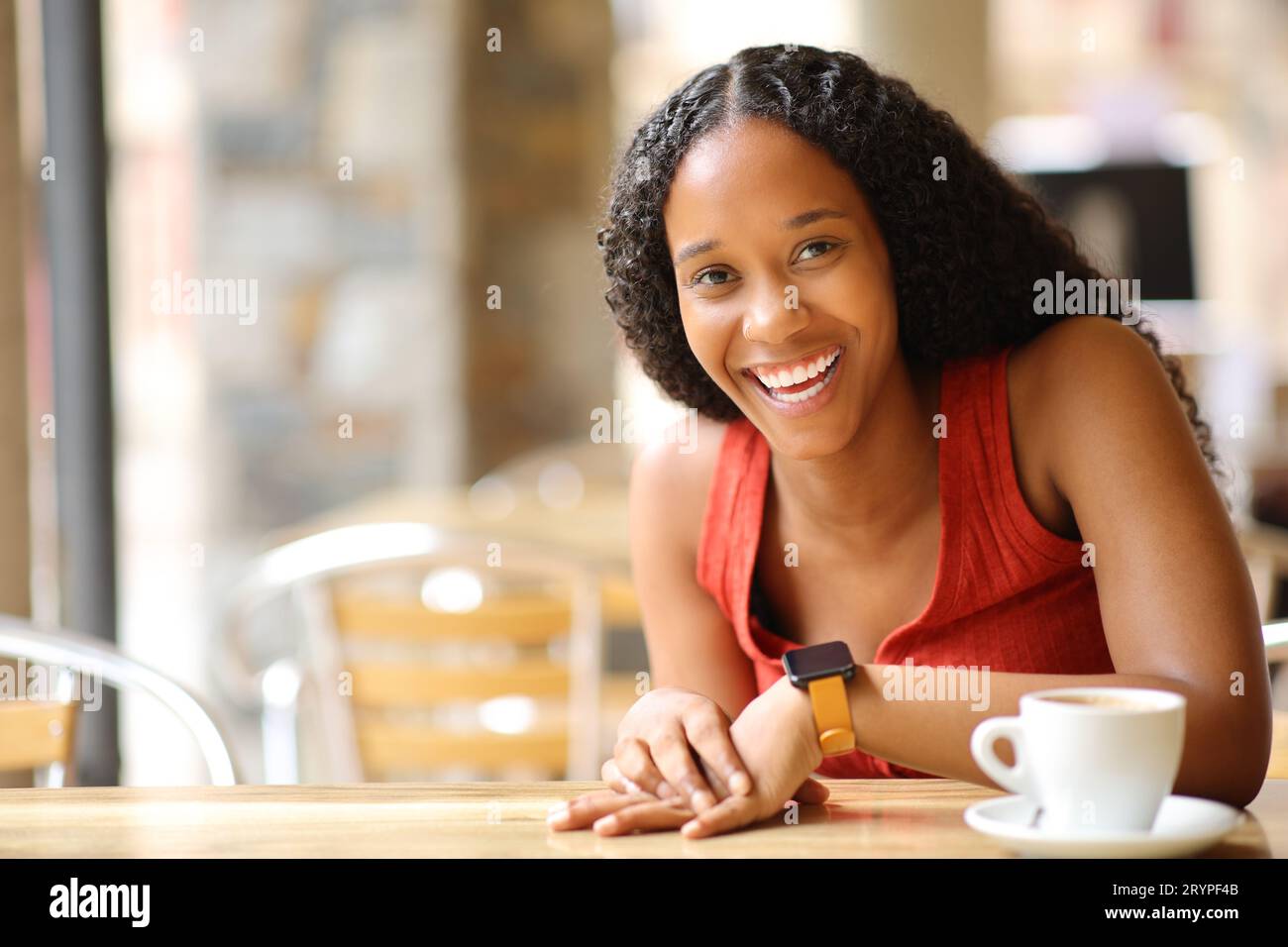 Glückliche schwarze Frau lacht, die auf einer Bar-Terrasse in die Kamera schaut Stockfoto