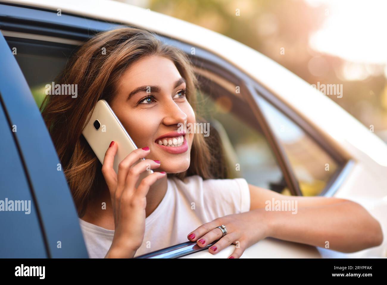 Attraktive Frau mit Telefon im Auto Stockfoto