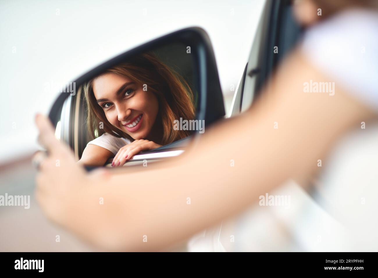 Portrait von Süß lächelnde Mädchen sitzen im Auto und schauen Sie sich das Auto Spiegel Stockfoto