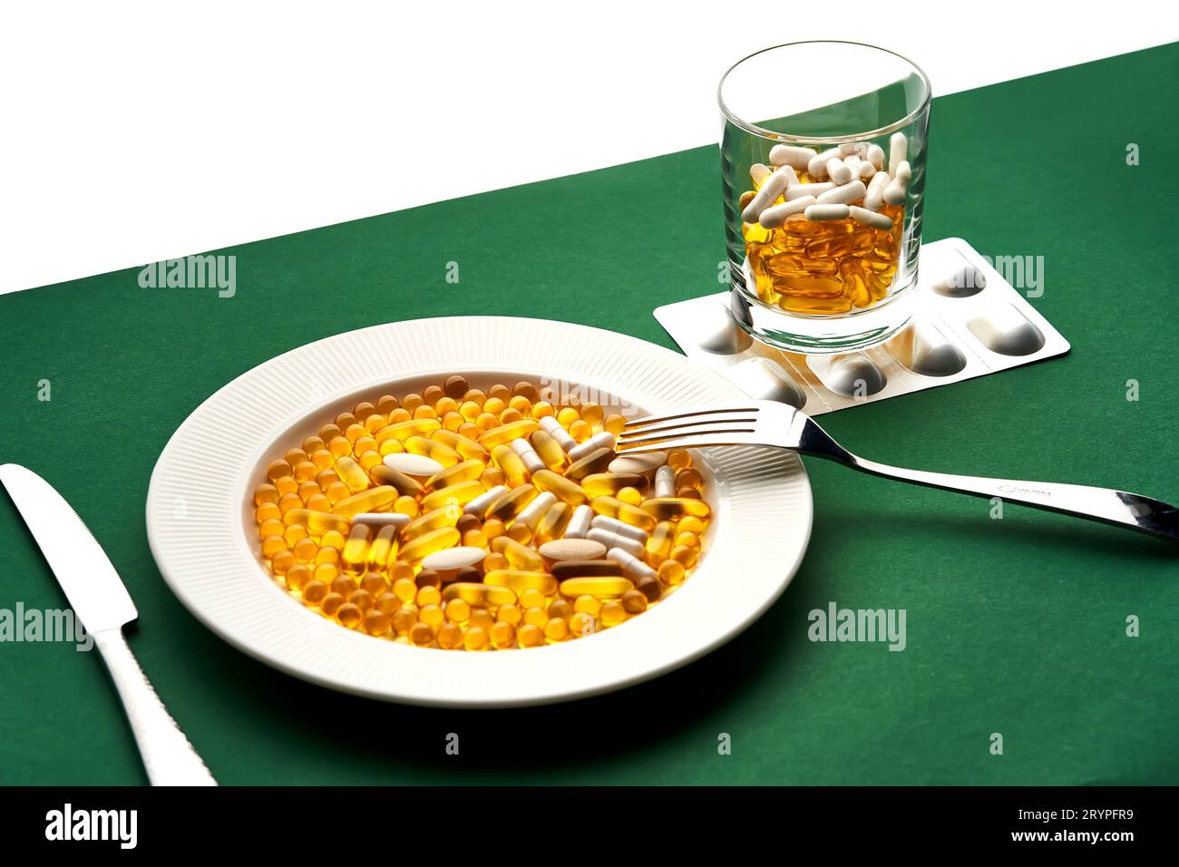 Ein Teller und ein Glas mit Vitaminen und anderen medizinischen Präparaten. Stockfoto