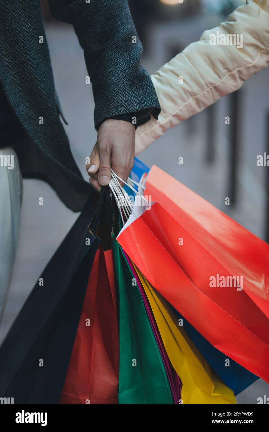 Einkaufstaschen in männlichen und weiblichen Händen. Übergabe von Taschen oder Geschenken, Nahaufnahme. Stockfoto