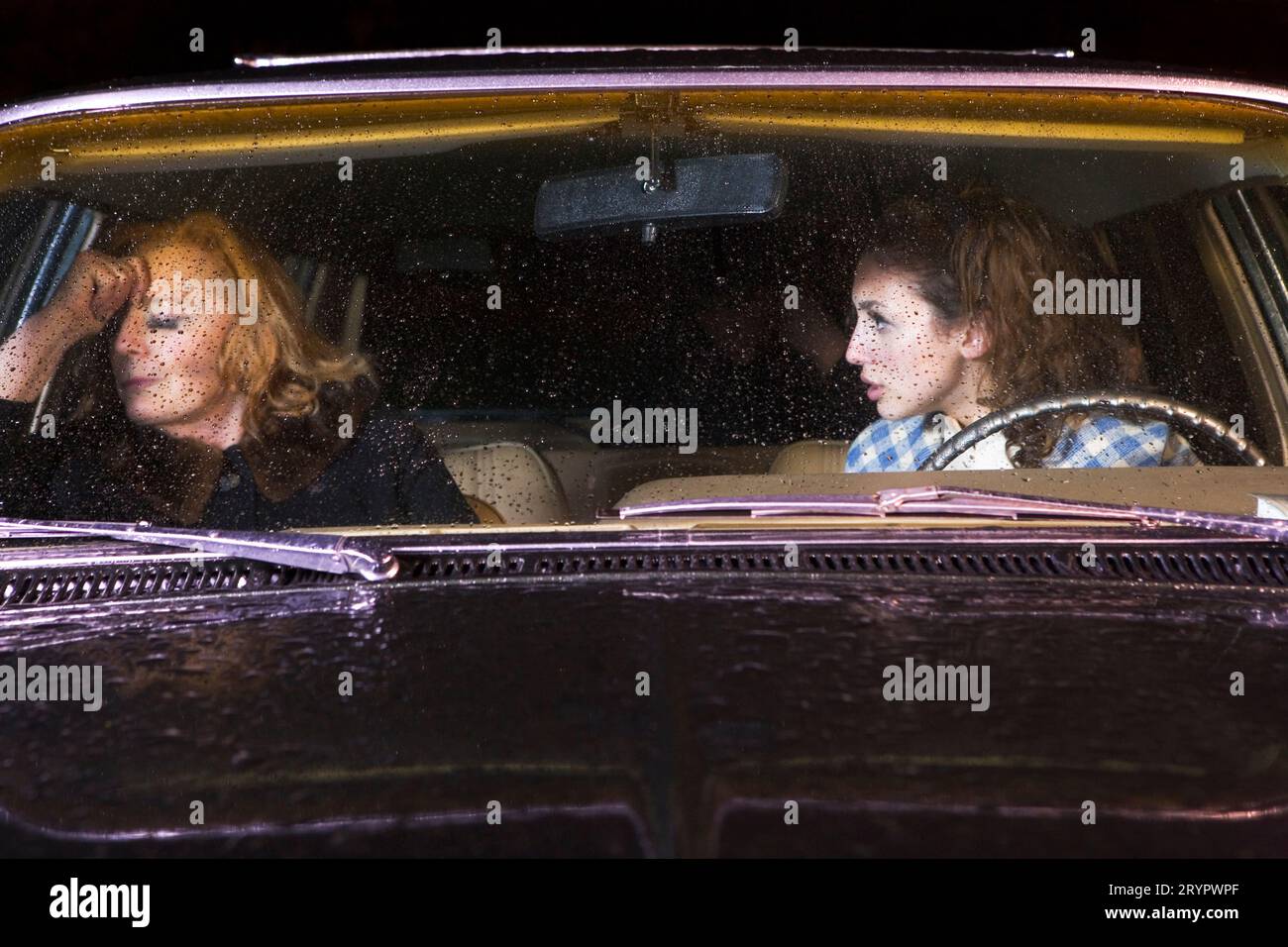 Nachts durch die Windschutzscheibe eines Autos streiten sich zwei Frauen auf dem Vordersitz. Stockfoto