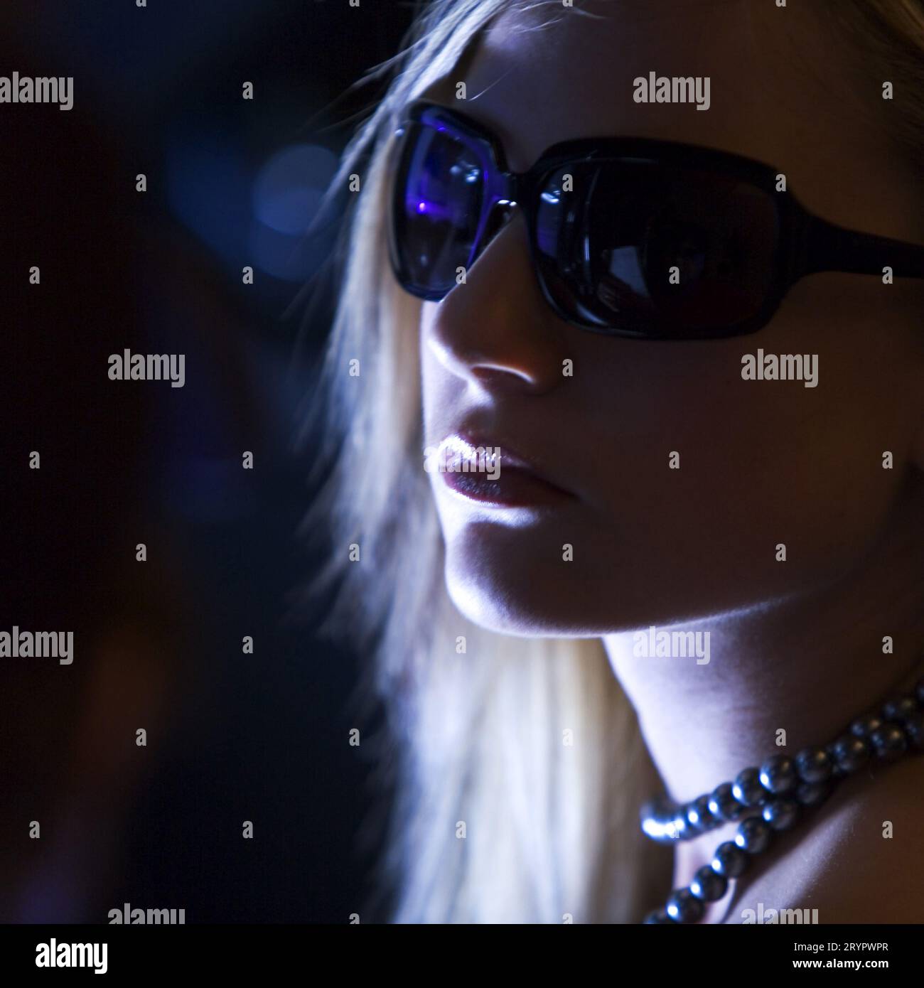 Porträt einer jungen blonden Frau in der Nacht mit dunkler Sonnenbrille. Stockfoto