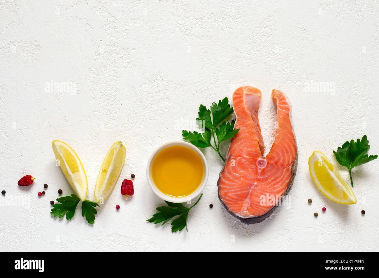 Frisches rohes Lachssteak, Olivenöl, Zitrone und Gewürze auf einem weißen B Stockfoto