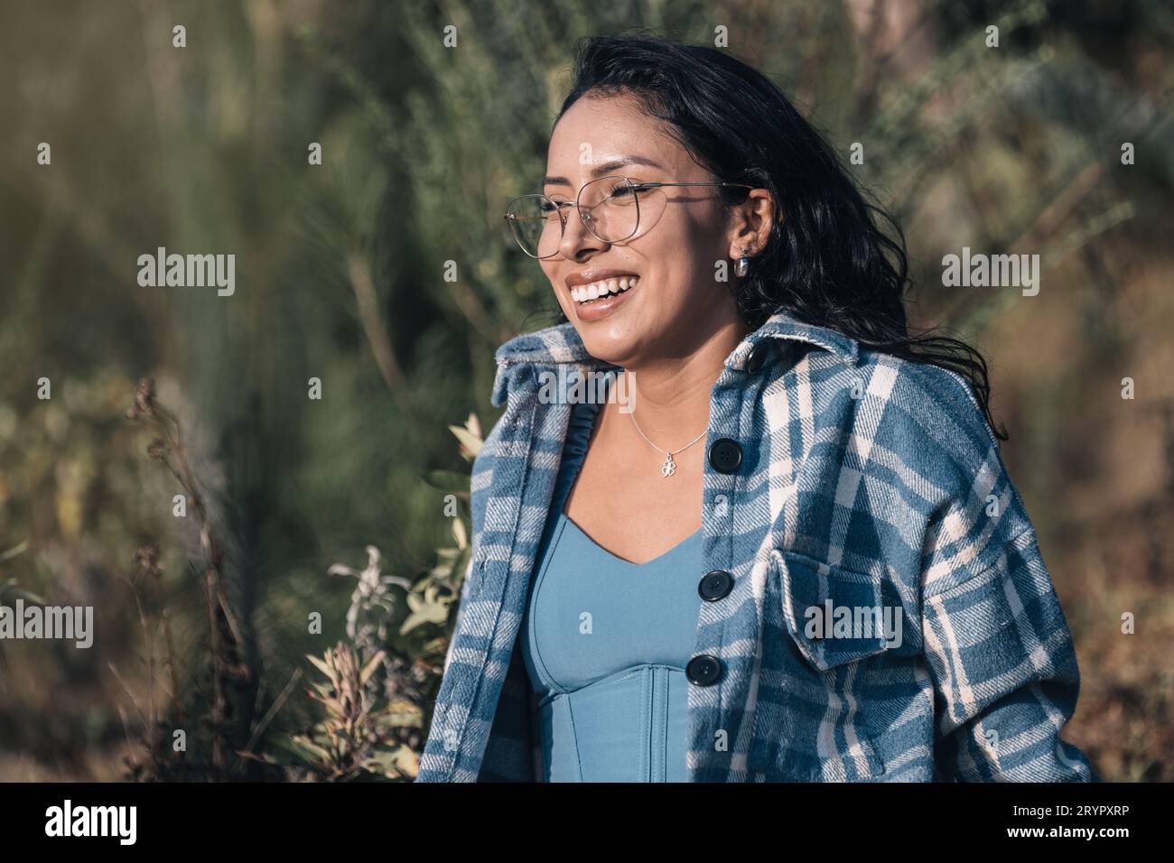 Eine schöne junge Frau mit Brille lächelt beim Sonnenuntergang in der Natur Stockfoto