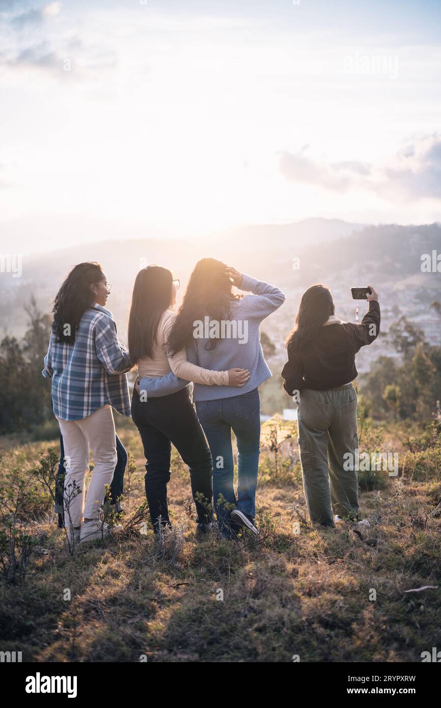 Rückansicht weiblicher Freunde, die ein Selfie bei Sonnenuntergang in den Bergen machen Stockfoto