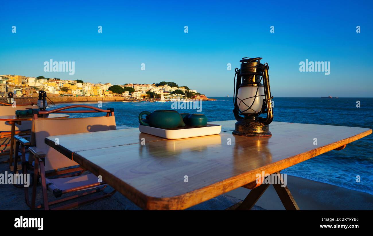Eine Nahaufnahme einer Vintage-Lampe und eine Teekanne auf einem Tisch in einem Café mit Blick auf das Meer Stockfoto