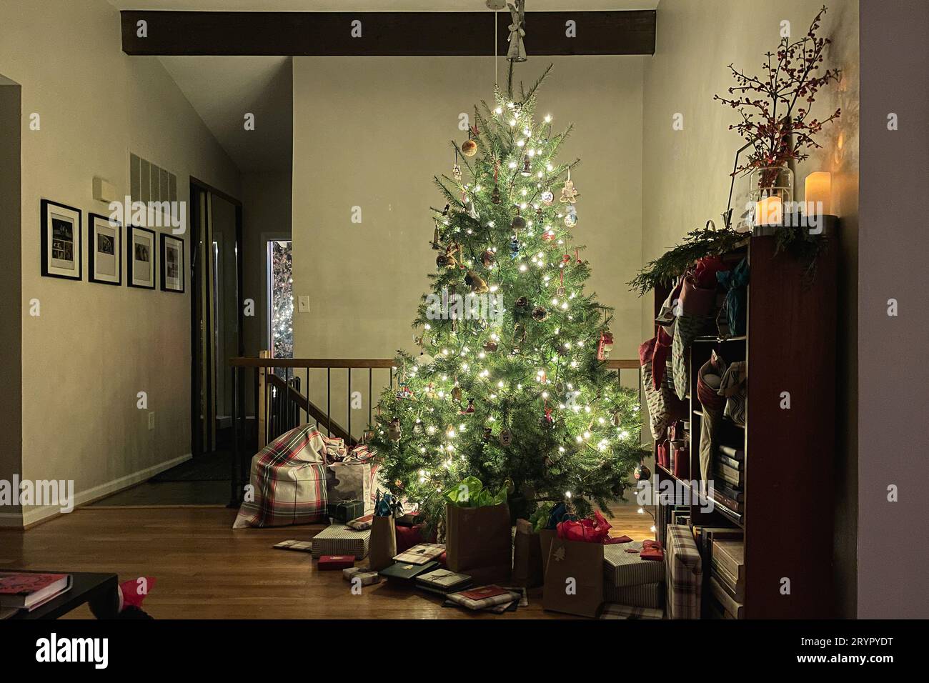 Eingewickelte Geschenke unter einem wunderschön beleuchteten weihnachtsbaum. Stockfoto