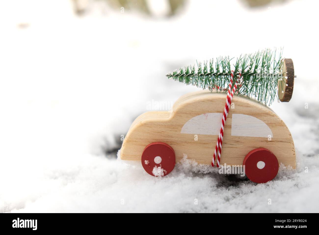 Holzwagen mit Weihnachtsbaum über Schnee. Kopierraum für Text Spielzeugauto in verschneite Landschaft. Frohe Weihnachten und frohes neues Jahr Stockfoto