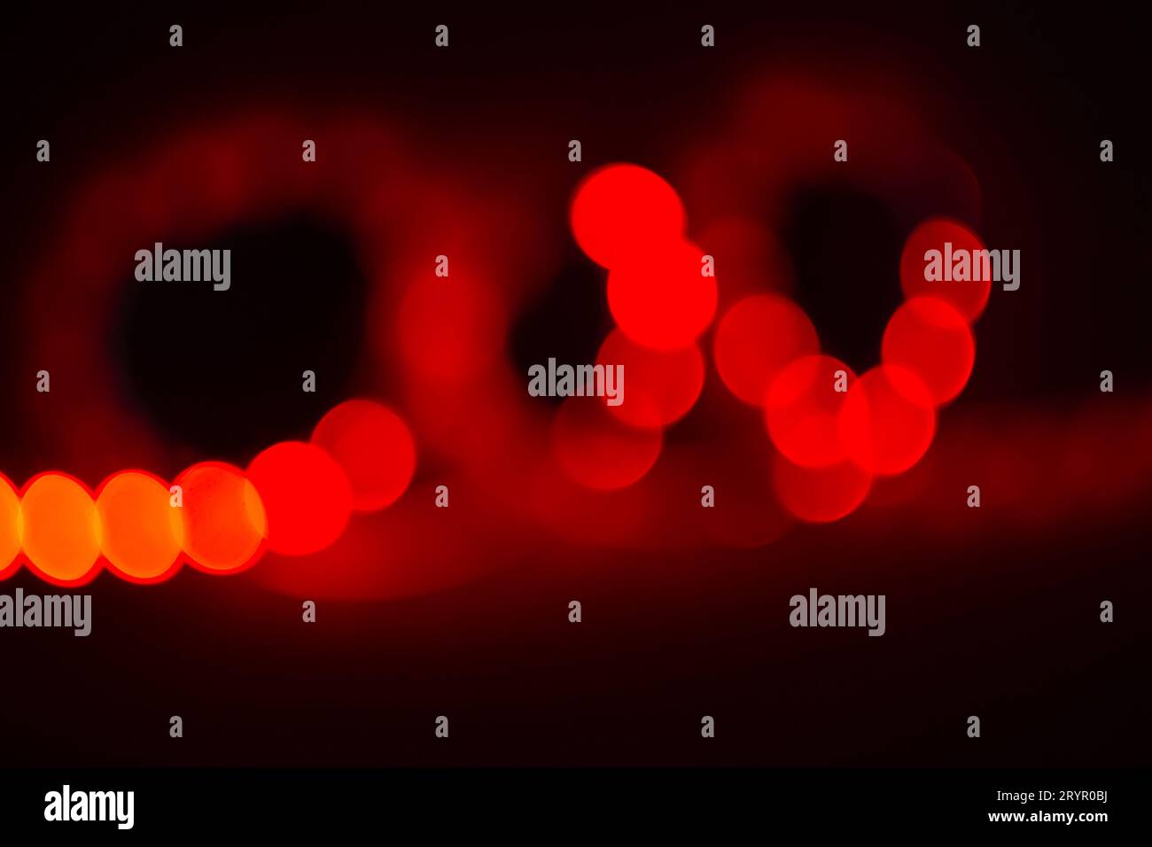 Rotes Neon verschwommene Locken von Bokeh-Lichtern auf Schwarz. Abstrakter Hintergrund der Farben der 80er Jahre Stockfoto