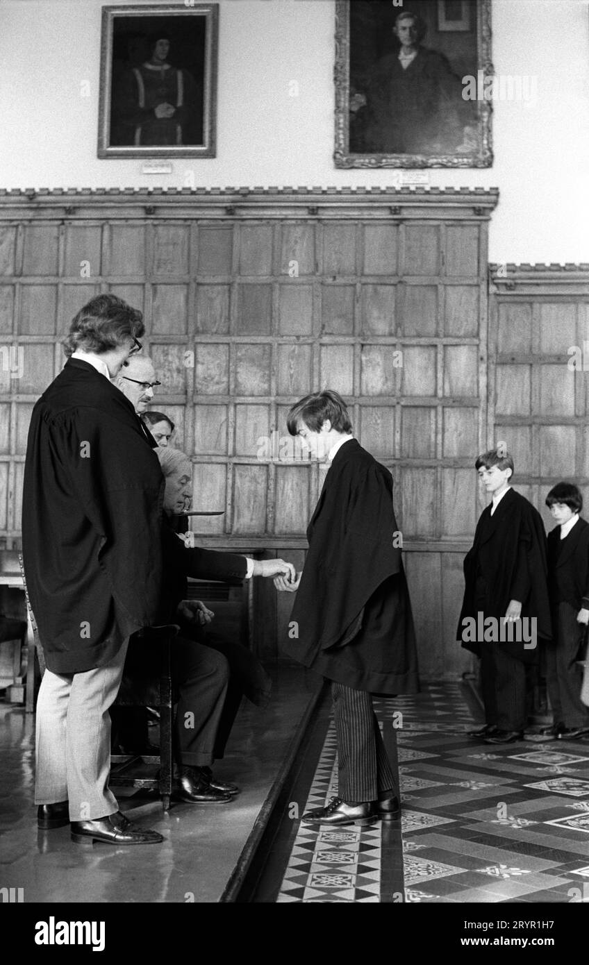 Eton College, Kings Scholars stellen sich zusammen und sammeln ihr jährliches traditionelles 3D-Stück vom College Provost. Diese Tradition, die als Threepenny Day bekannt ist, ist 400 Jahre alt. Die jährliche Verteilung erfolgte nach dem Mittagessen in der College Hall durch den Provost Harold Caccia (Provost 1965–1977) und war auf die siebzig Könige Gelehrten beschränkt. Eton, Windsor, Berkshire, England, 27. Februar 1975. 1970ER JAHRE UK HOMER SYKES Stockfoto