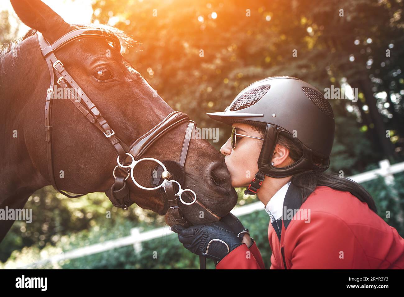 Ein junges Mädchen Jockey im Gespräch mit ihrem Pferd. Sie liebt die Tiere und verbringt freudig ihre Zeit in ihrer Umgebung. Stockfoto