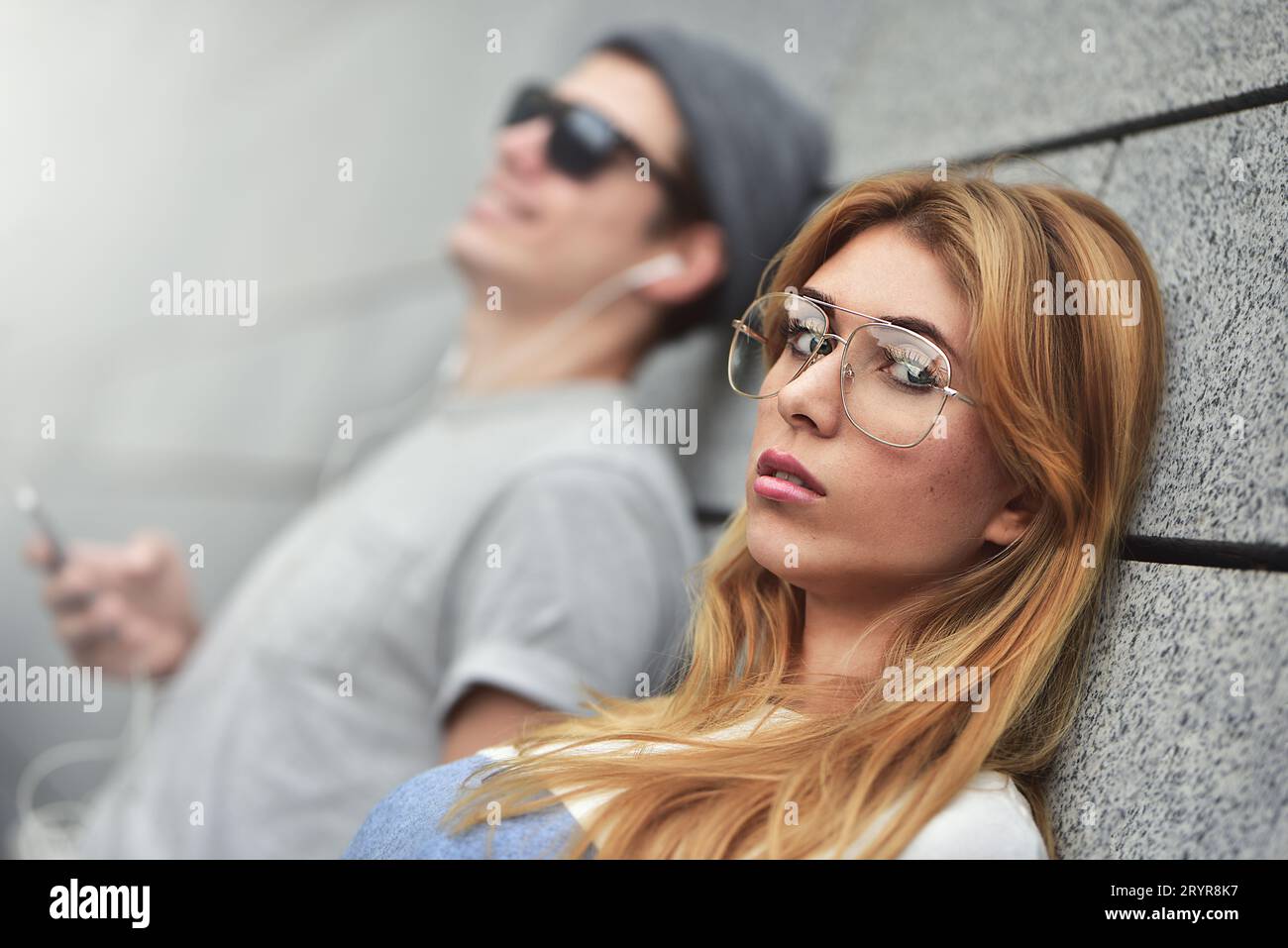 Junge attraktive Paare, die Musik auf denselben Kopfhörern hören, in stilvoller Kleidung vor einem Hintergrund eines Stockfoto