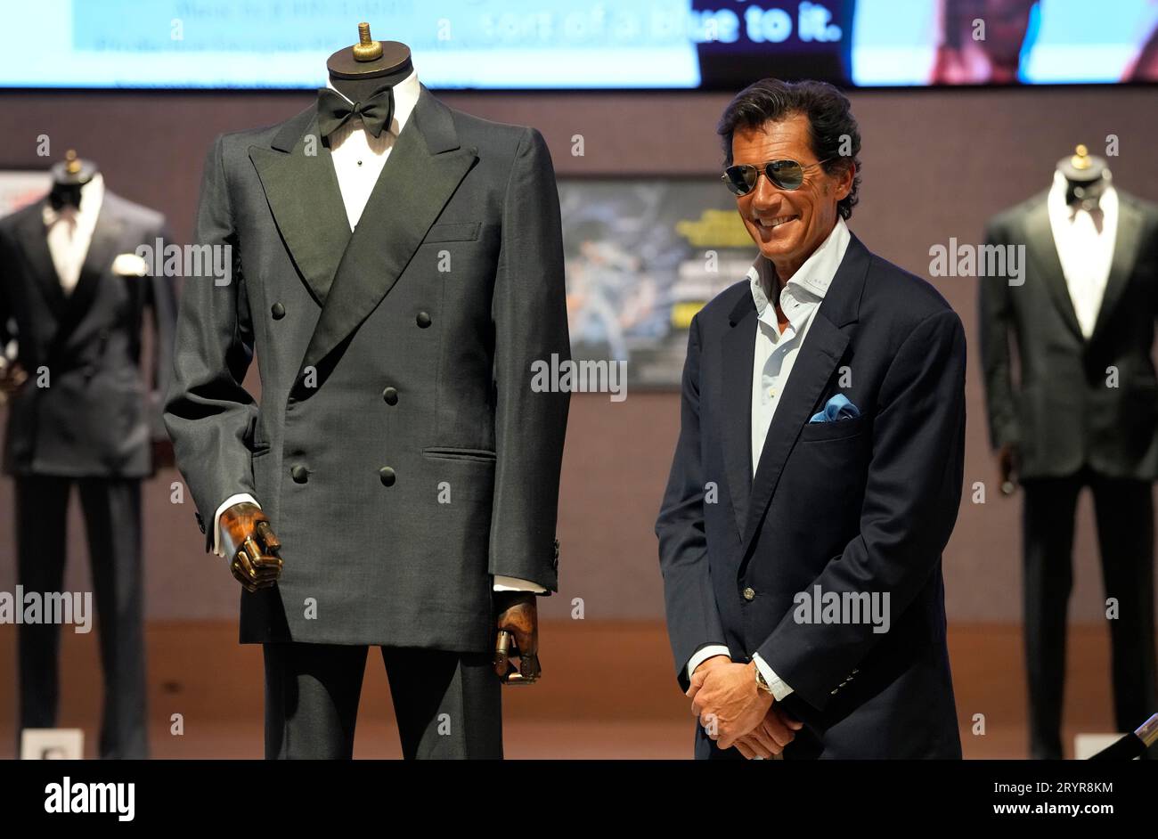 Geoffrey Moore, son of Sir Roger Moore, stands with a James Bond mohair double-breasted dinner suit worn by Sir Roger for the Eiffel Tower scene in A View to a Kill, including two pairs of trousers estimated at £20,000 - 30,000, part of the 'Sir Roger Moore: The Personal Collection sale', at Bonhams auction rooms in London, Monday, Oct. 2, 2023. The 180-lot sale of his personal collection is being offered directly by Sir Roger Moore's family, and will include important James Bond memorabilia, collectables and personal ephemera.The auction will take place on Oct. 4 in London. (AP Photo/Kirsty W Stockfoto