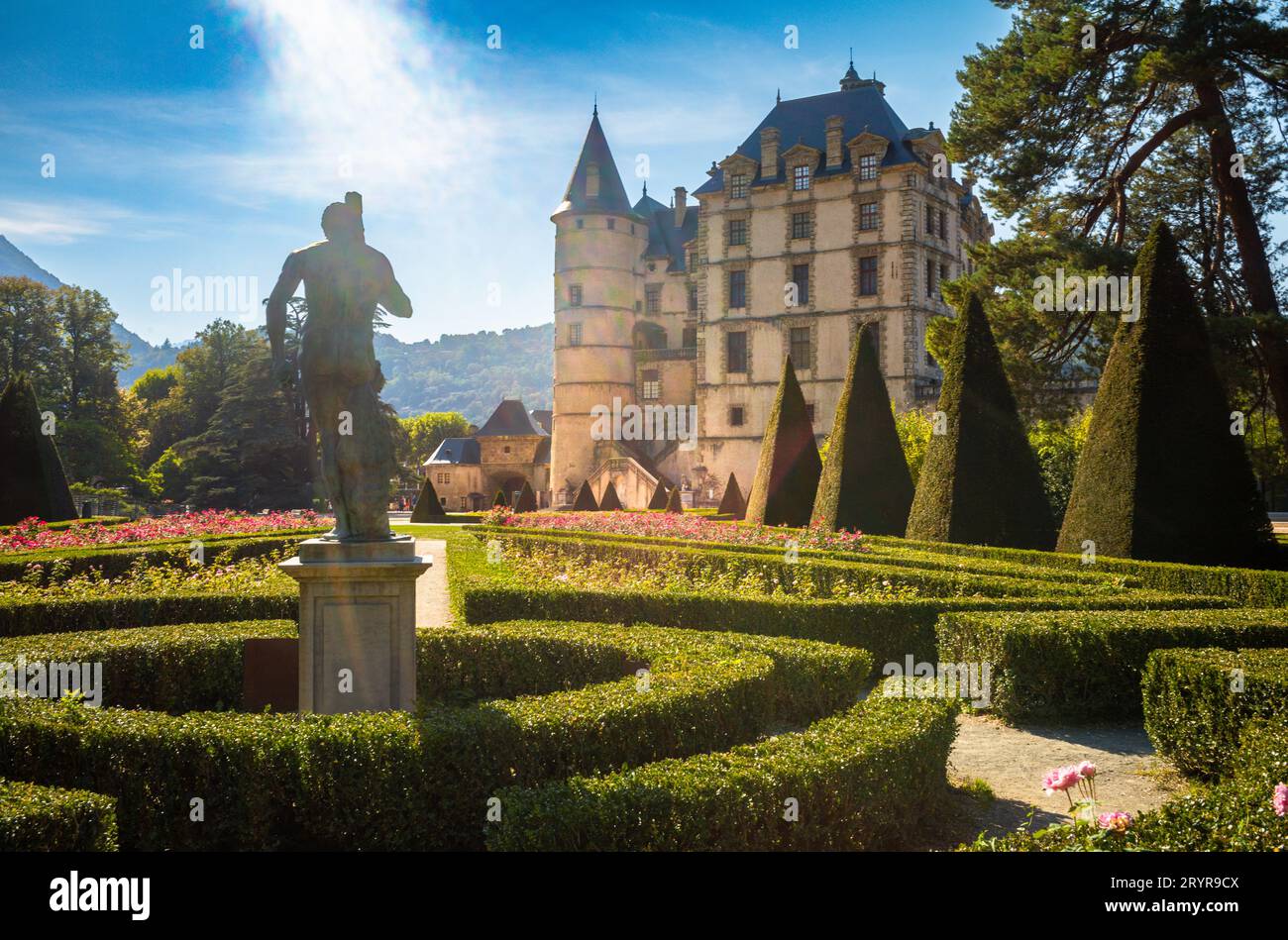 Ein Blick vorbei an einer großen Statue über die formellen Gärten des Schlosses mit dem Museum der Französischen Revolution, Vizille, Frankreich. Stockfoto
