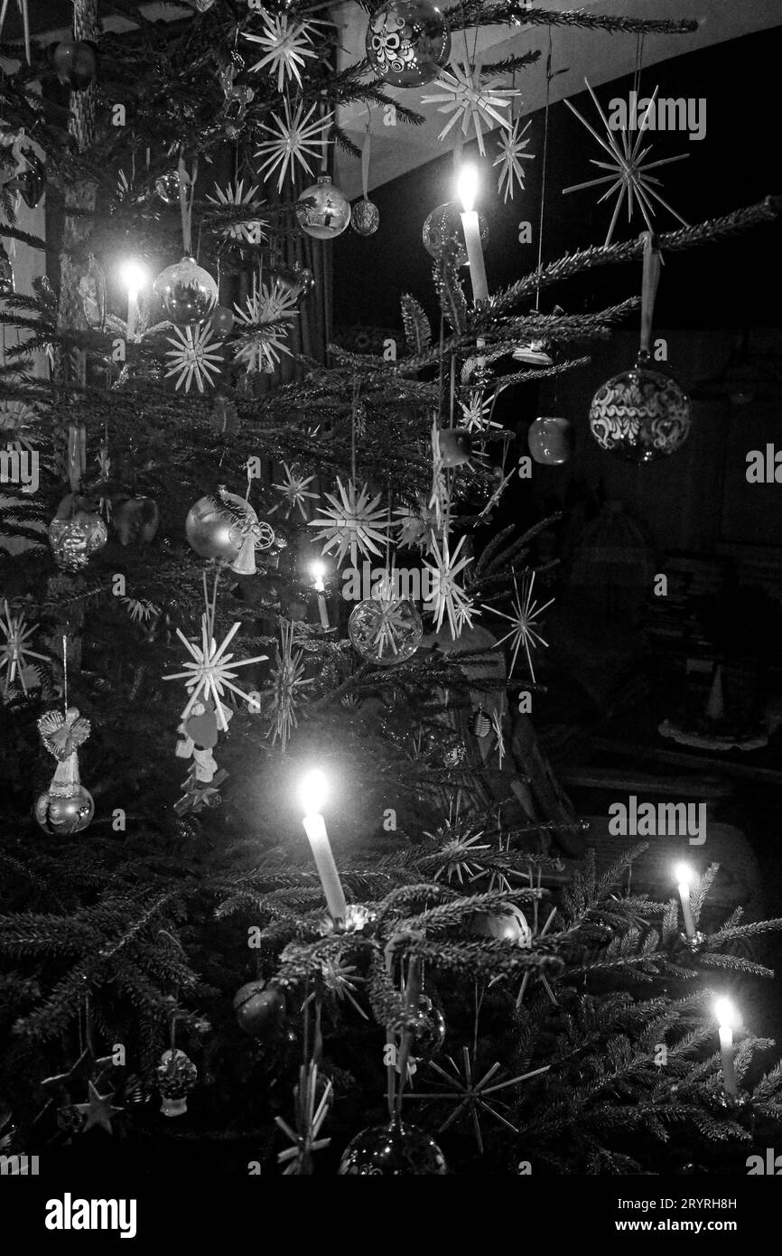 Ein weihnachtliches Schwarz-weiß-Bild eines Weihnachtsbaums mit beleuchteten Kerzen und Sterndekorationen, perfekt für die Weihnachtszeit Stockfoto