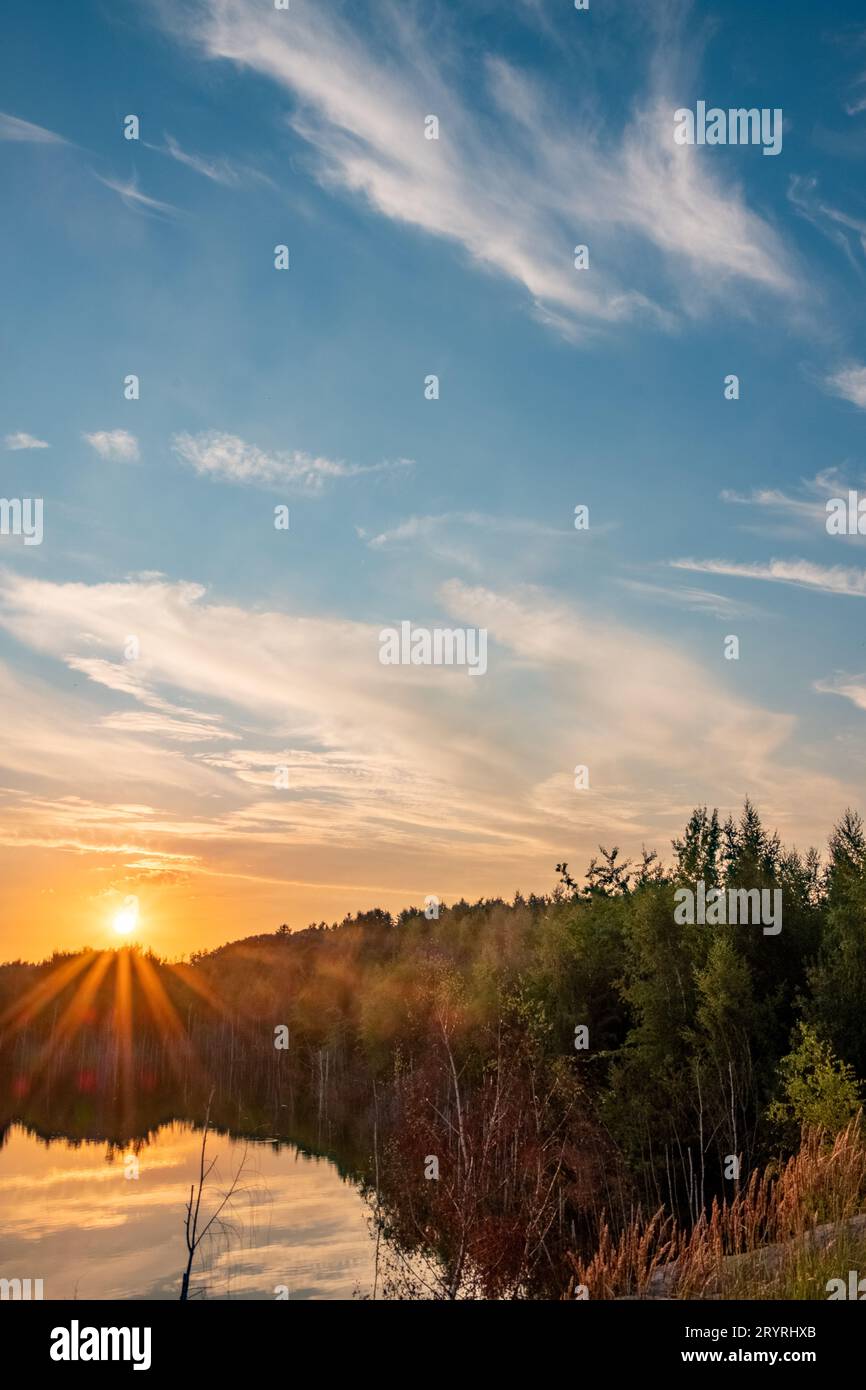 Wunderschöne Landschaft mit farbenfrohem Sonnenuntergang über dem Waldsee, epischen roten und goldenen Wolken über dem Waldsee bei Sonnenaufgang. Dramatisch Stockfoto