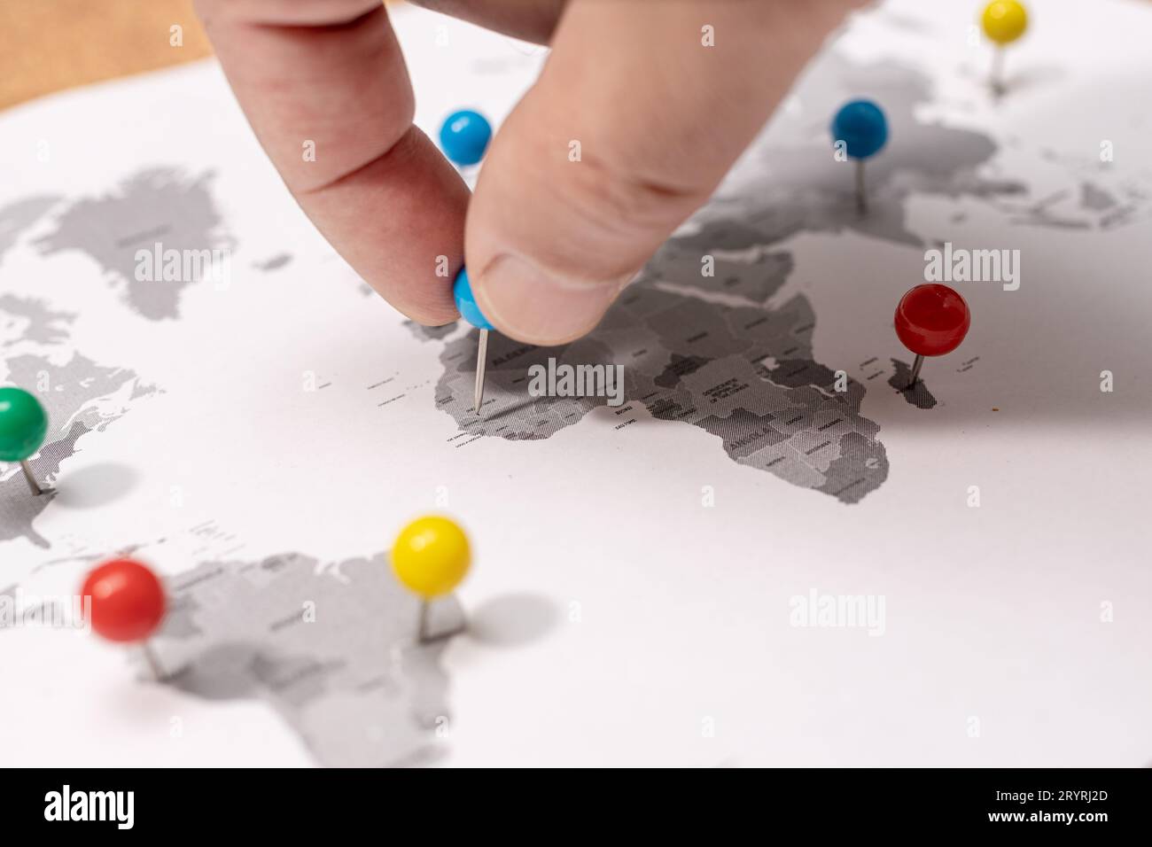 Nahaufnahme der menschlichen Hand, die auf der Weltkarte feststeckt. Konzept für Reiseziele Stockfoto