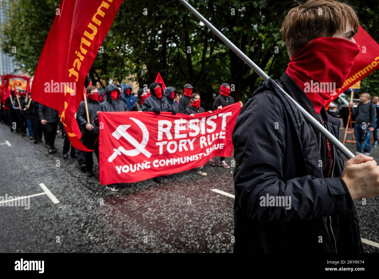 Der Kommunistische Jugendbund marschiert mit einem Banner, das seine Meinung während der Demonstration zum Ausdruck bringt. Während der Konservativen Partei-Konferenz marschierten die Menschen durch die Stadt, um eine nationale Demonstration durchzuführen. Die Forderungen, die von der Volksversammlung organisiert und von Gewerkschaften unterstützt werden, umfassen die Beendigung der Lebenshaltungskrise und die Verteidigung des NHS. Stockfoto