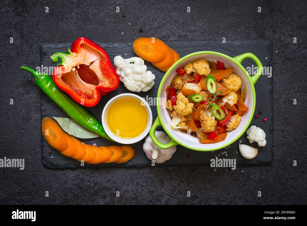 Schüssel mit gedünstetem Gemüse-Ragout und rohen Zutaten. Gesundes, Vegetarisches Lebensmittelkonzept Stockfoto