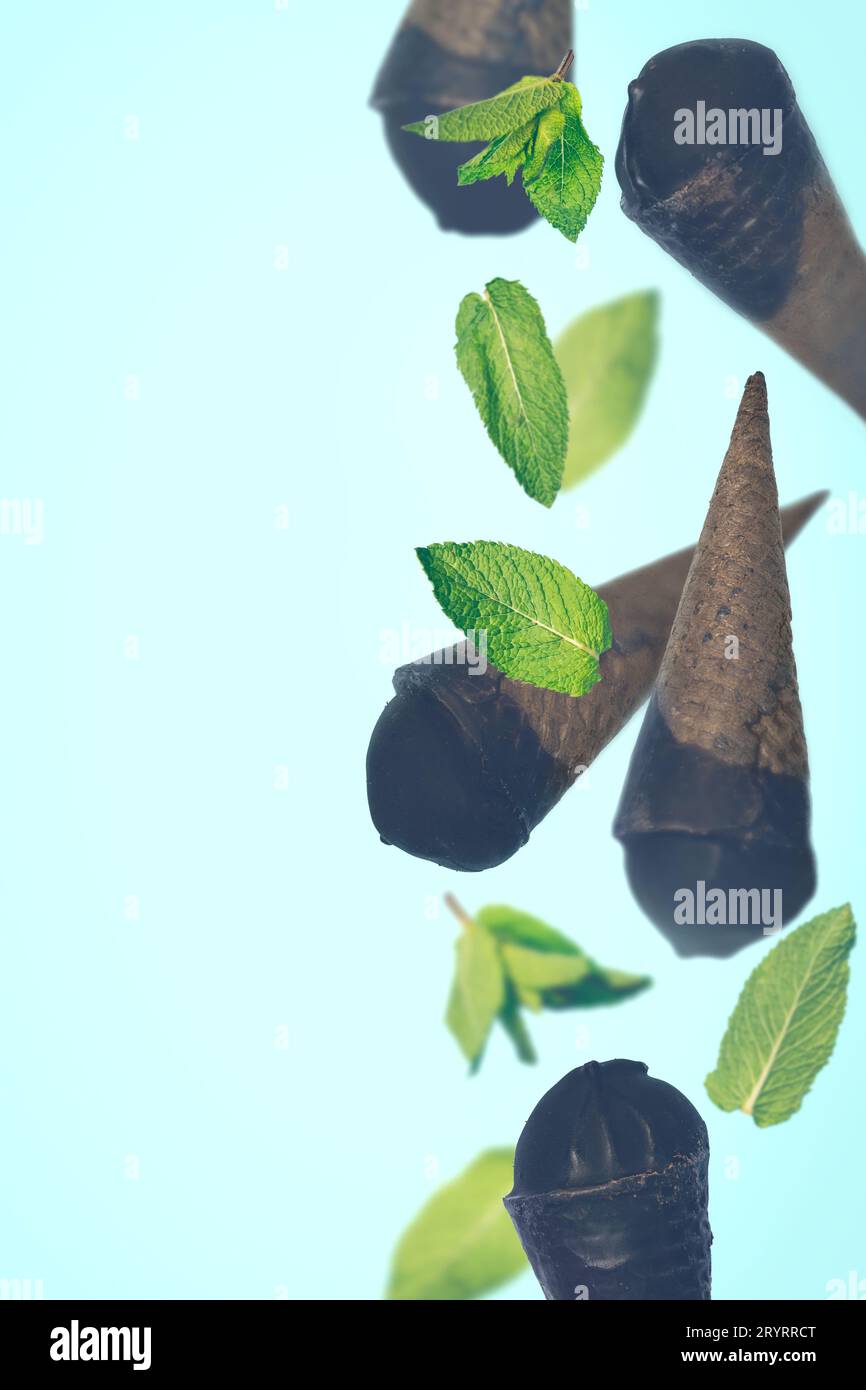 Schwarzes Eis in Waffelkegeln auf pastellfarbenem Hintergrund Stockfoto