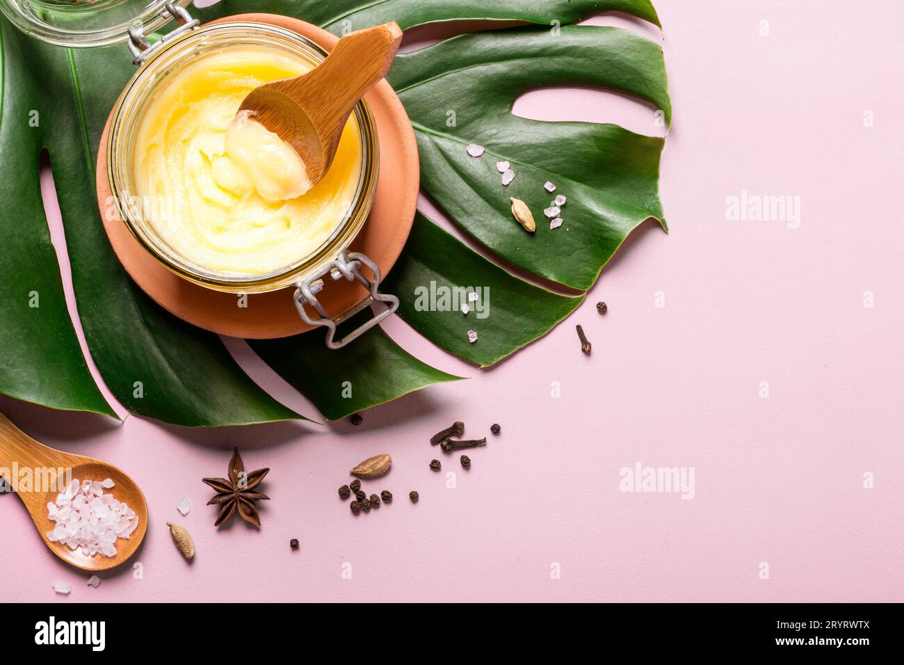 Ghee-Butter im Glas, rosa Salz und Gewürze auf rosa Hintergrund Stockfoto