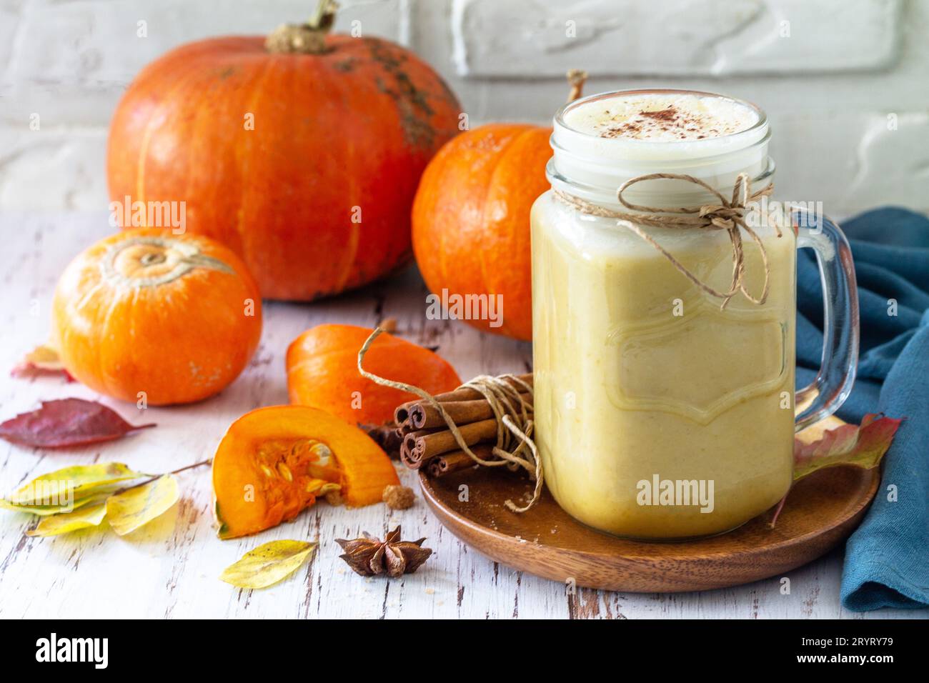 Herbstgetränk. Kürbis gewürzter Latte oder Kaffee im Glas auf einem rustikalen Holztisch. Stockfoto