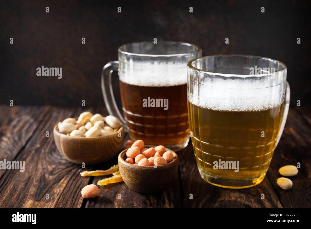 Alkohol Trinkpint von Lager und Pint von Stout, Craft Beer. Zwei Gläser Bier mit Schaum und Snacks auf rustikalem Holzhintergrund. Stockfoto