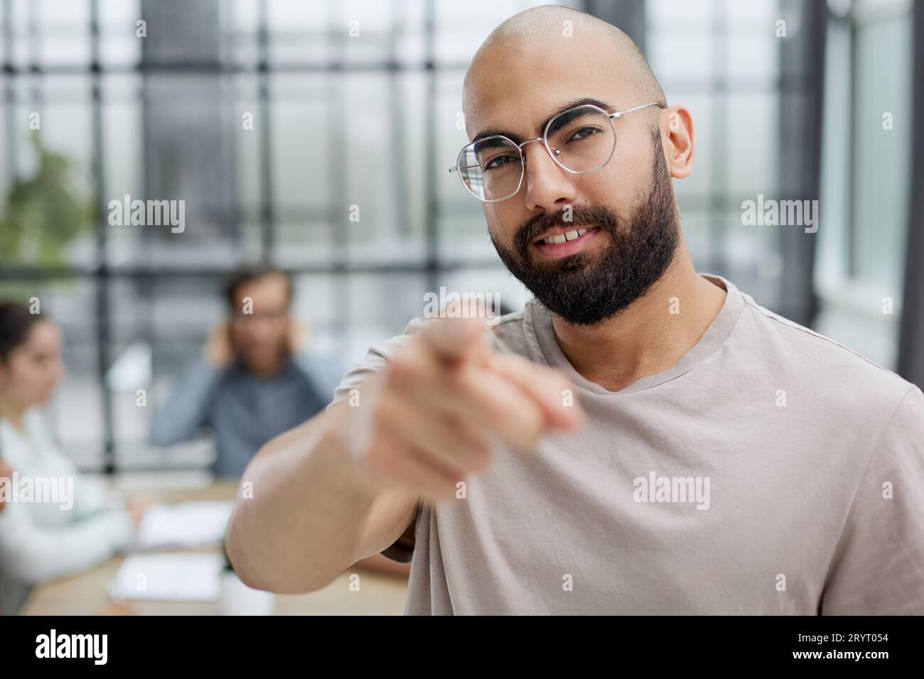 Lässiger Bärtiger Geschäftsmann, Der Lächelnd Auf Ihr Büro Zeigt Stockfoto