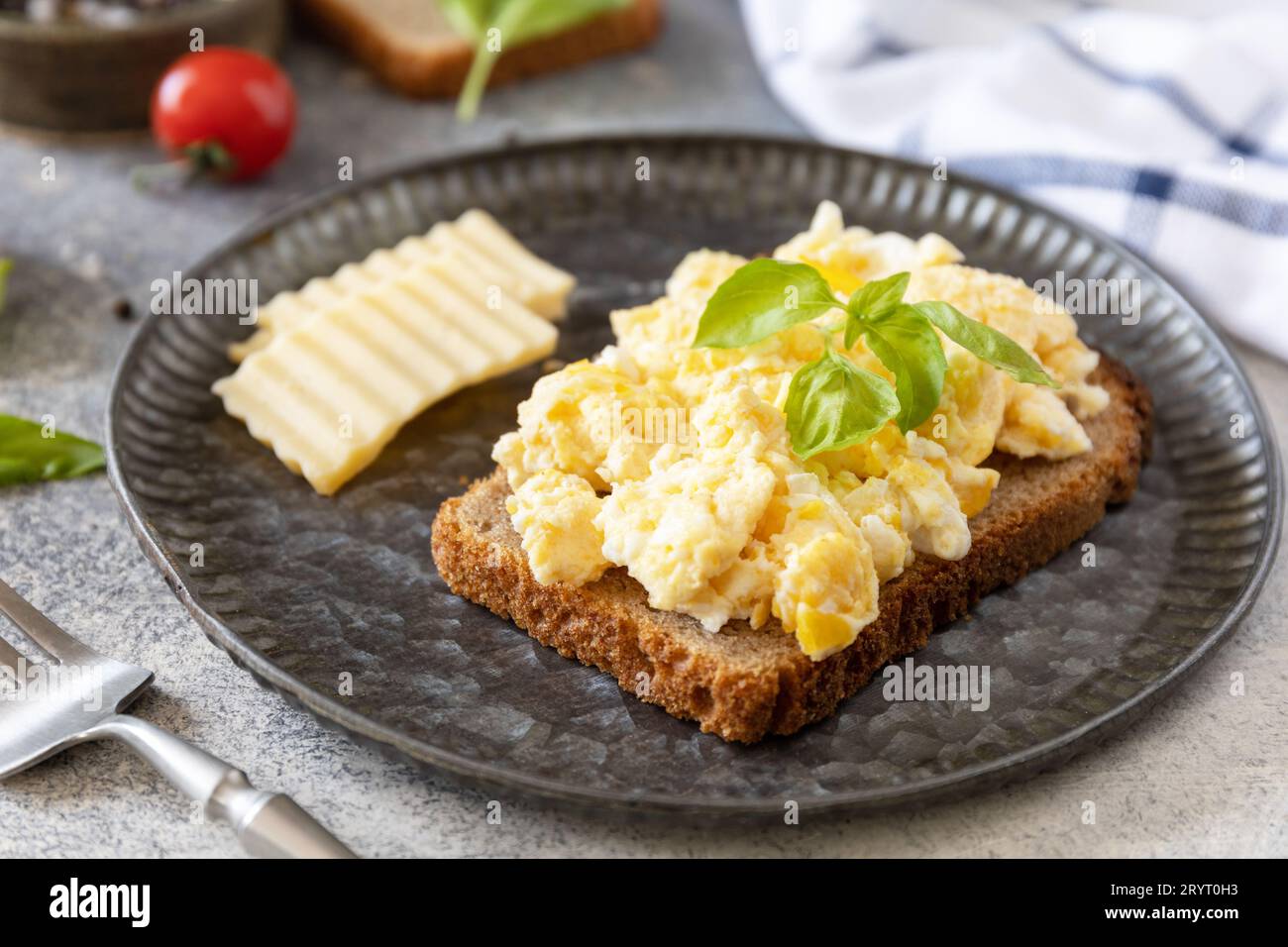 Hausgemachtes Frühstück oder Brunch - Rührei. Rührei auf Vollkornbrot auf einem Steintisch. Stockfoto