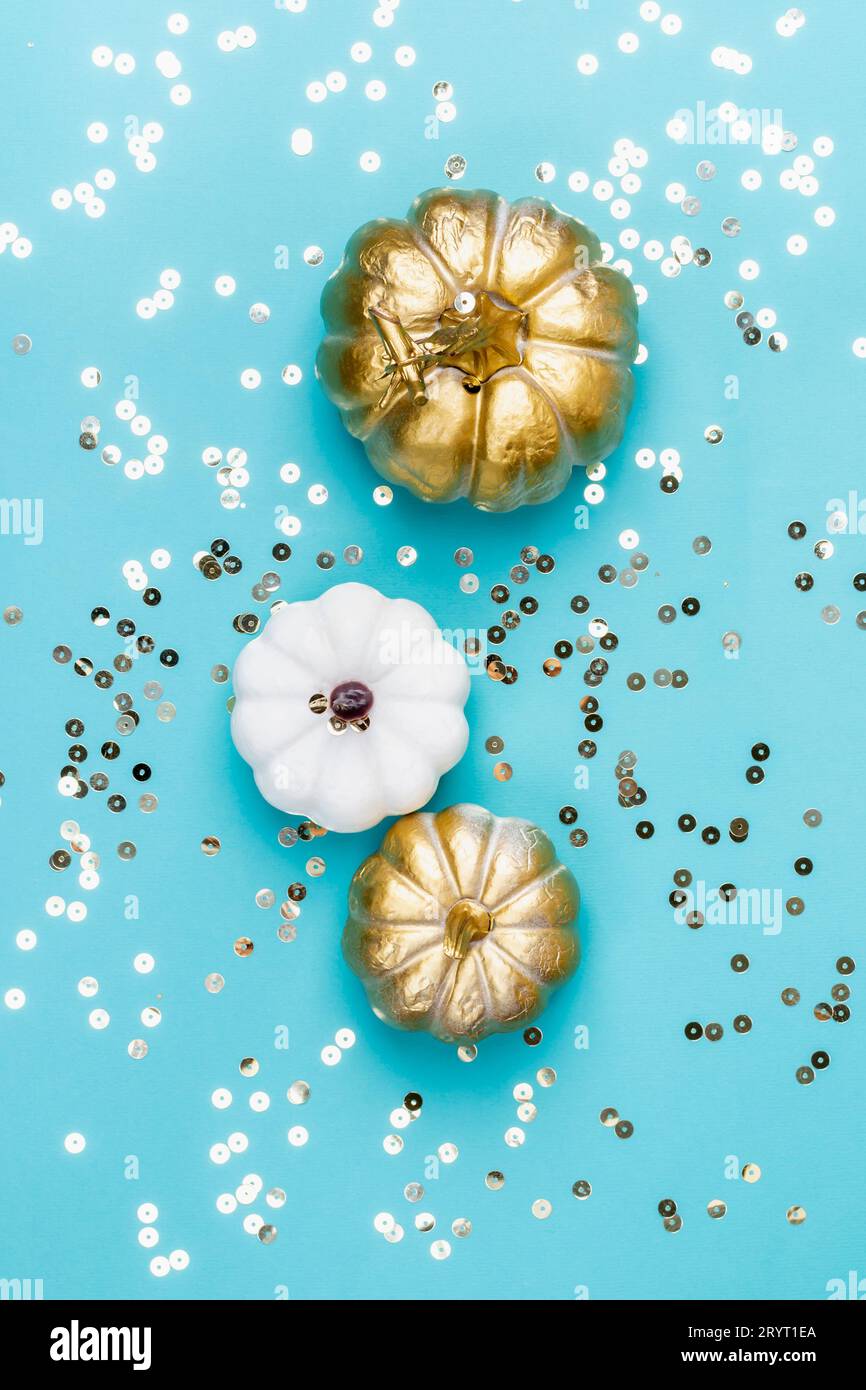 Festliche Komposition aus goldenen Kürbissen und Funkeln auf blauem Hintergrund. Herbst-, Halloween- oder Thanksgiving-Konzept Stockfoto