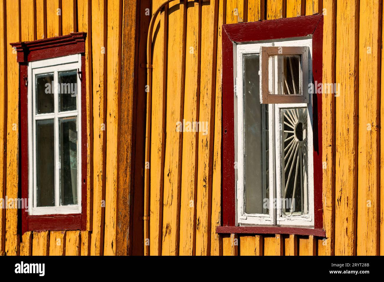 Gelbe hölzerne Hauswand mit Holzfenstern Stockfoto