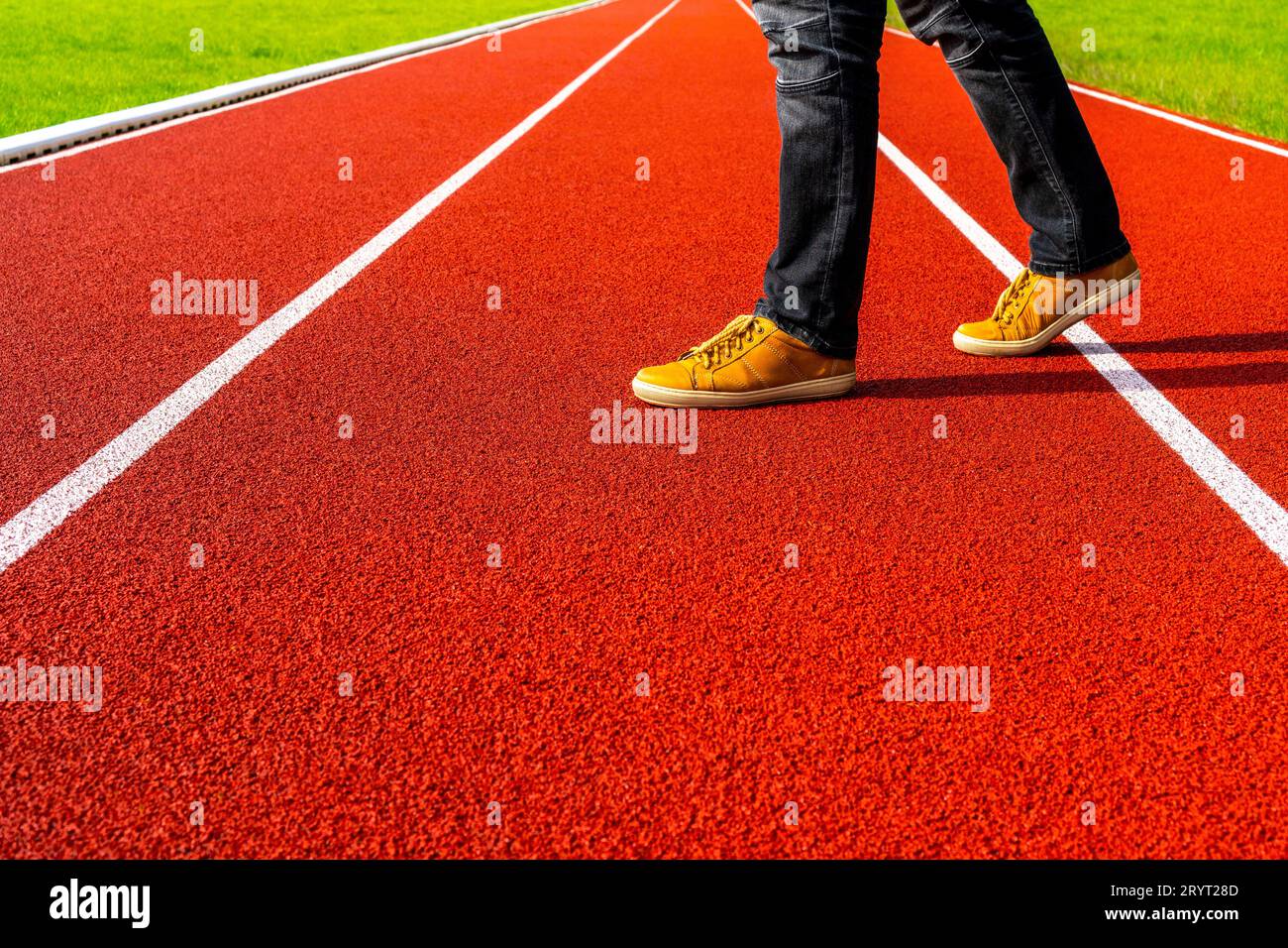 Ein Mann in braunen Sneakers und schwarzen Jeans läuft über die Laufstrecke Stockfoto