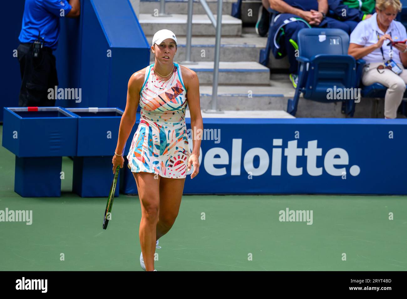 Eine junge Frau in einem Tennisoutfit ist mitten auf dem Platz, Schläger in der Hand, bereit, einen Ball zu schlagen Stockfoto