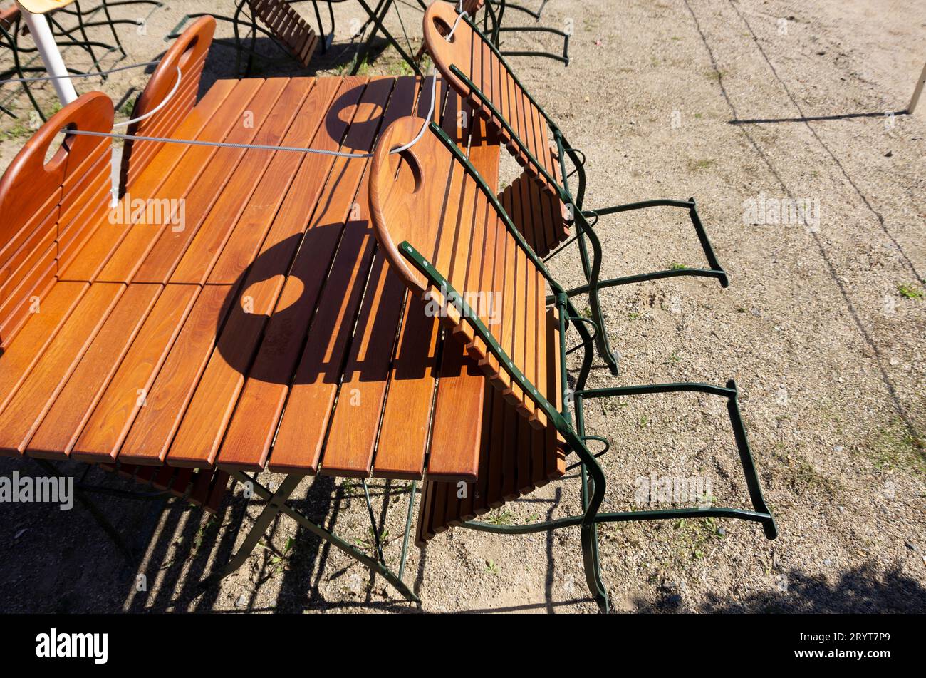 Vier Stühle stehen an einem Biergartentabtisch und sind mit einem Seil gesichert. Stockfoto