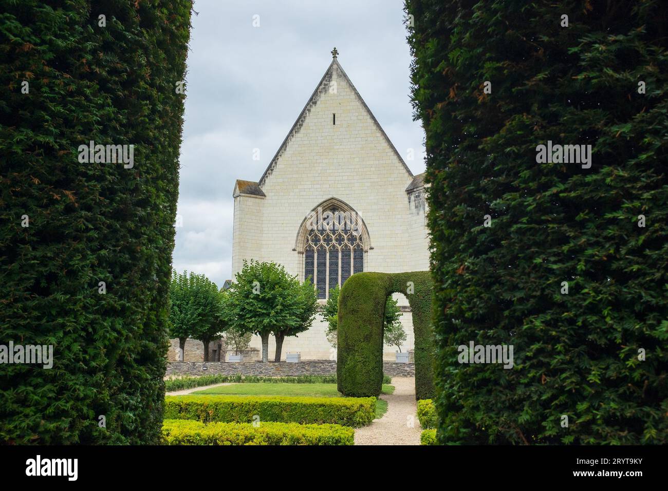 Angers, Frankreich, 2023. Die Kapelle der königlichen Unterkünfte aus dem 15. Jahrhundert, die durch den Bogen einer Eibenlaube im formellen Garten gesehen wird Stockfoto