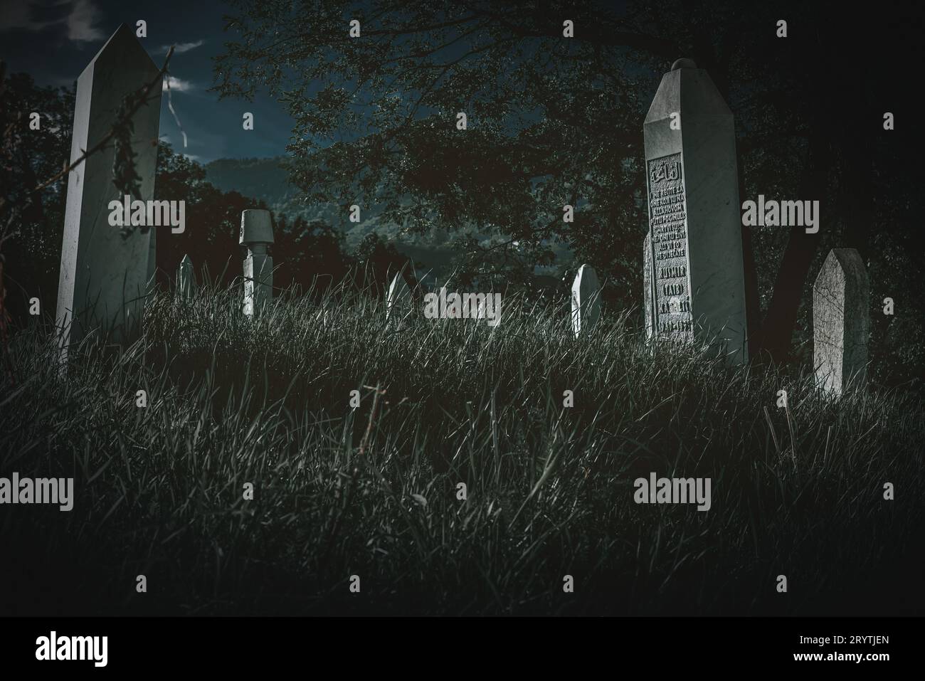 Ein unheimlicher Friedhof, der vor einem tiefblauen Nachthimmel steht und eine gruselige Atmosphäre schafft Stockfoto