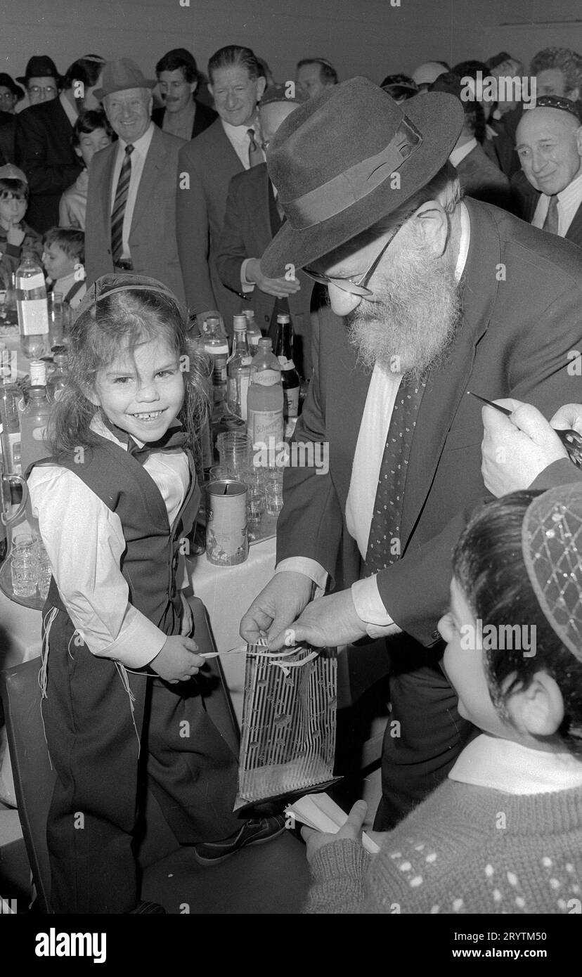 Die Upshernish erste Haarschneidezeremonie für einen dreijährigen jüdischen Jungen. Es ist eine altehrwürdige jüdische Tradition, einem Jungen das Haar in den ersten Lebensjahren unberührt wachsen zu lassen.1 an seinem dritten jüdischen Geburtstag werden Freunde und Gemeindemitglieder zu einer festlichen Haarschneidezeremonie eingeladen: Das Hochgefühl („Scheren“) auf Jiddisch oder Chalakah auf Hebräisch. Hier ist Yehudah lieb Sohn des Rabbiners Herschel Rader von der Solihull-Gemeinde das glückliche Thema. Der Großvater des Jungen wird mit dem ersten Schnitt geehrt, der die Menge in einen Beutel für seine Mutter und dann Mitglieder der Gemeinde einspart Stockfoto