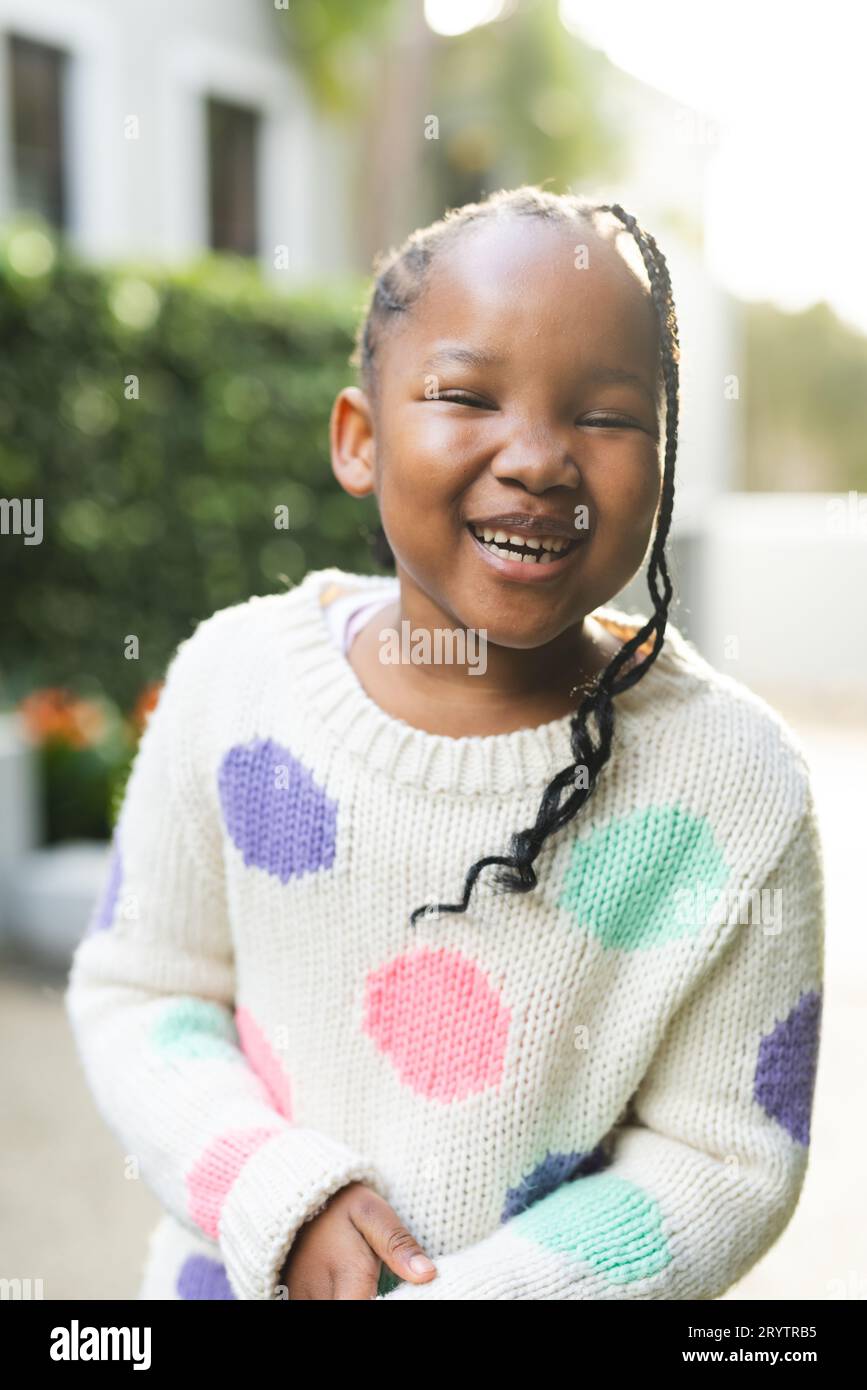 Porträt eines glücklichen afroamerikanischen Mädchens mit Zöpfen, die vor dem Haus stehen Stockfoto