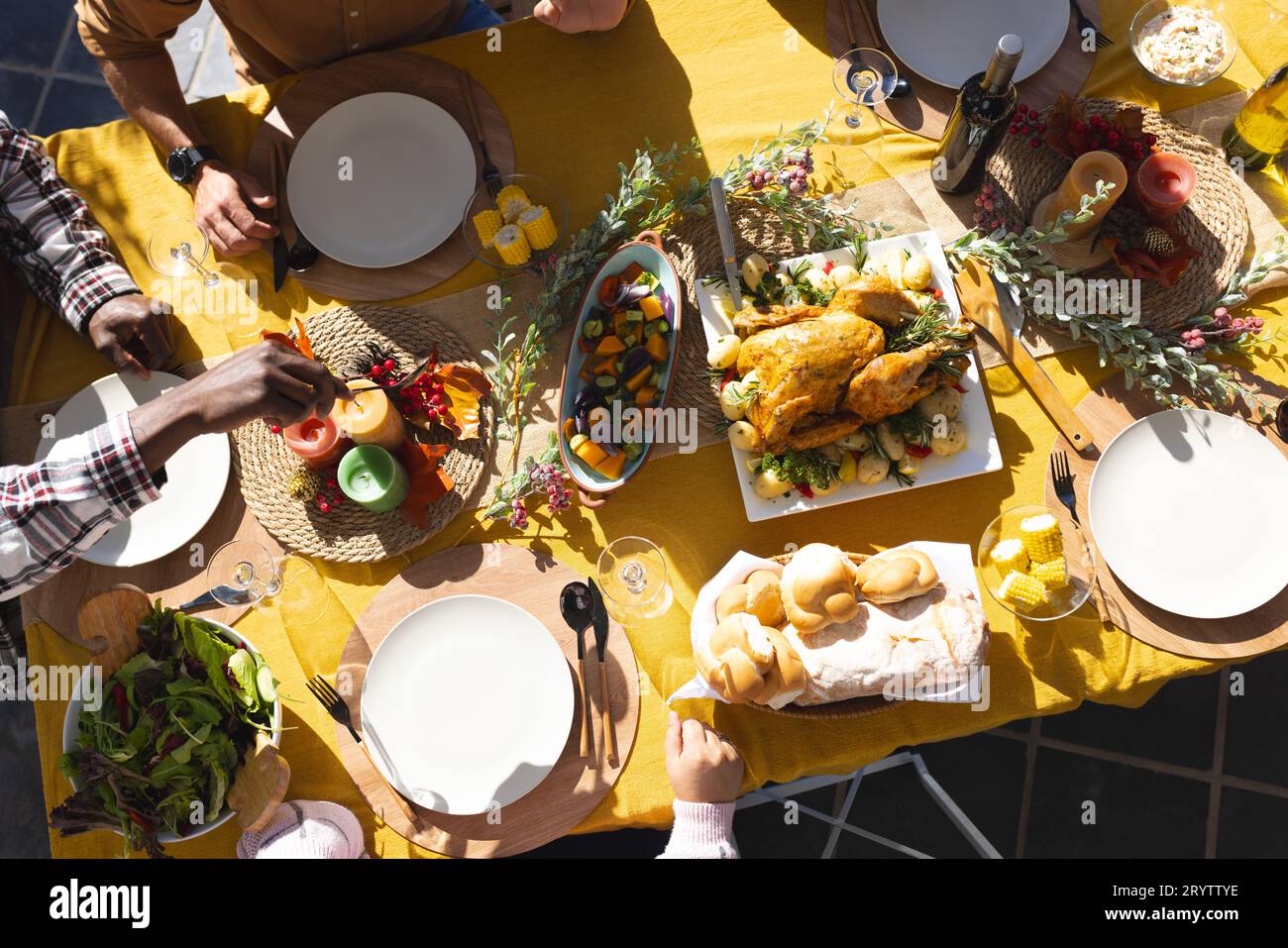 Fröhliche, vielfältige männliche und weibliche Freunde servieren Thanksgiving-Festmahlzeiten im sonnigen Garten Stockfoto