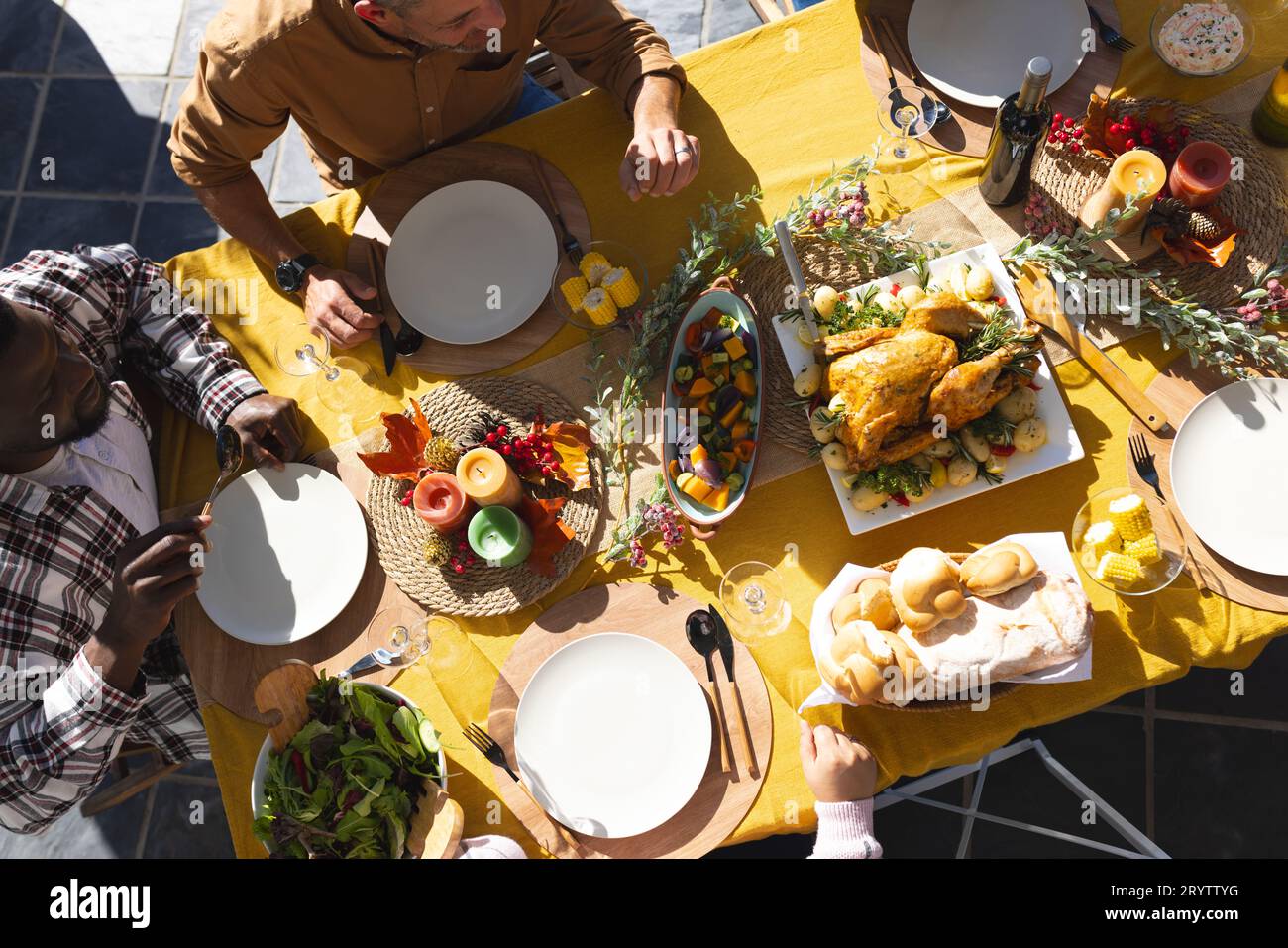 Fröhliche, vielfältige männliche und weibliche Freunde servieren Thanksgiving-Festmahlzeiten im sonnigen Garten Stockfoto