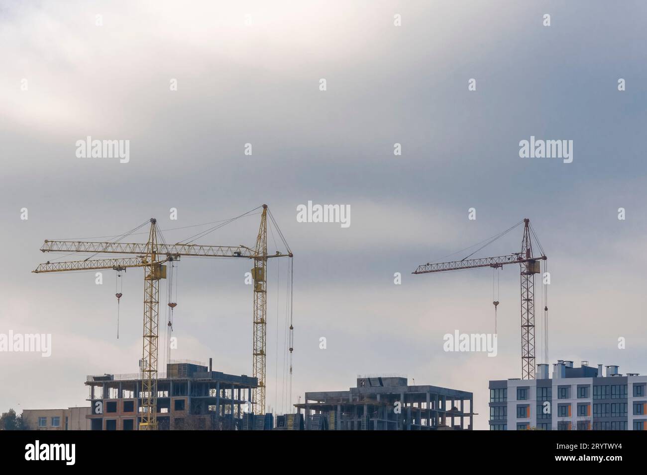 Kräne gegen blauen Himmel bauen. Turmkräne, Konzeptneubau, Immobilien, Wohnungen Stockfoto